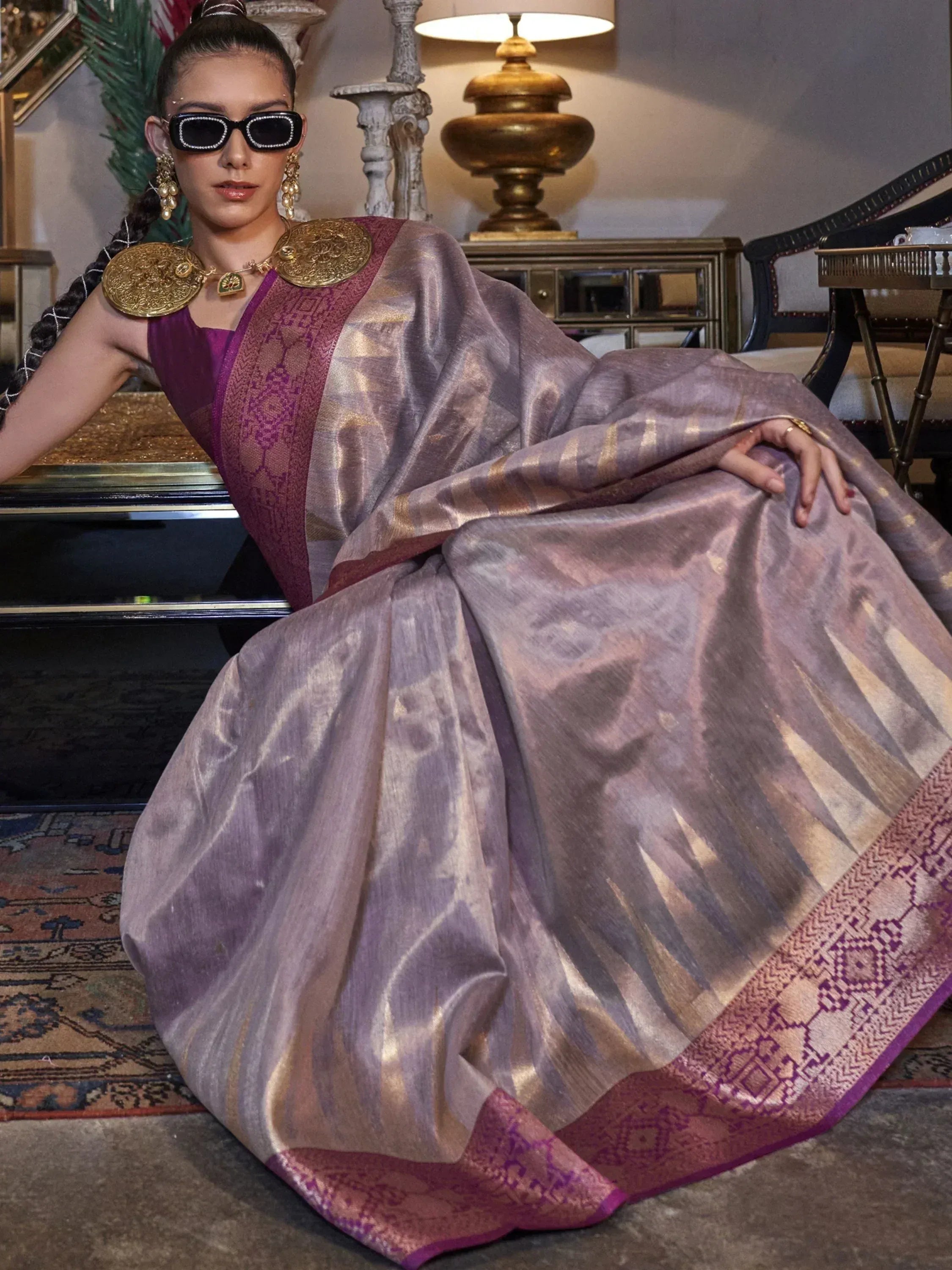 Elegant purple and gold ethnic saree with intricate border, styled with statement jewelry for festive occasions.