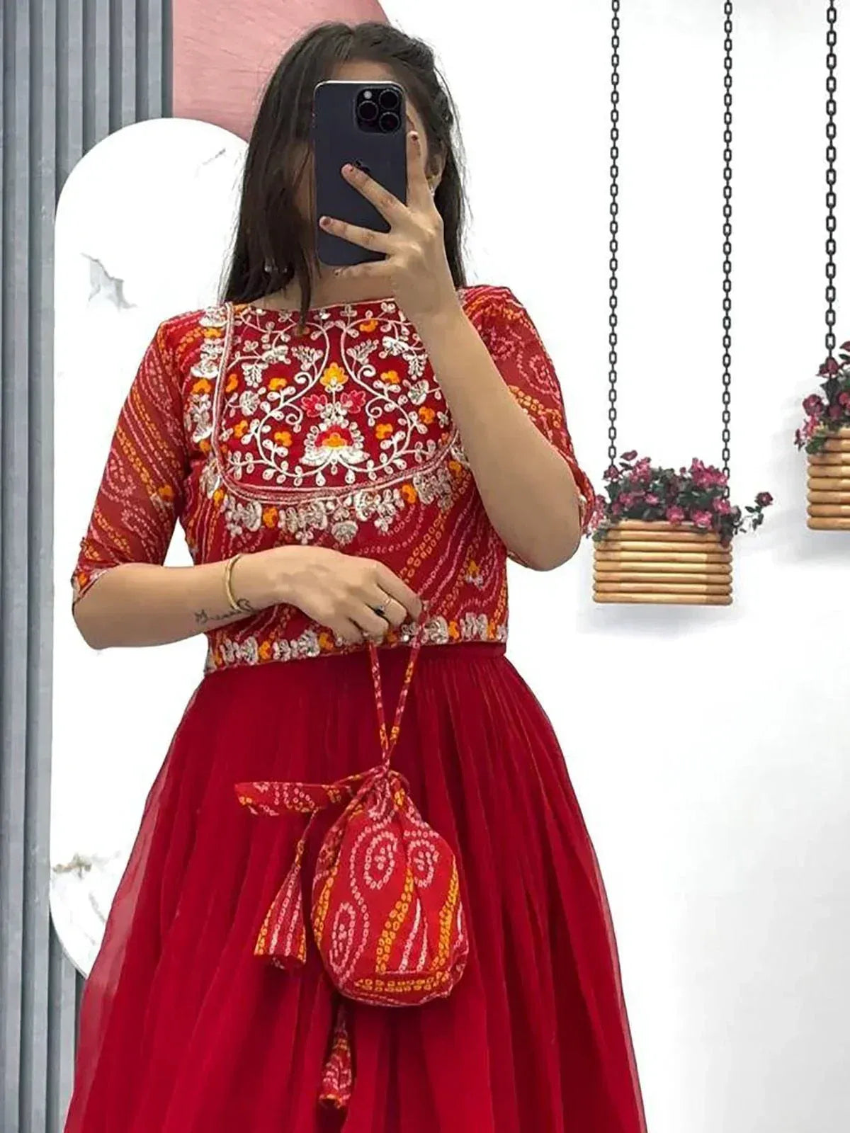 Red embroidered ethnic gown with matching potli bag, perfect for Indian occasions and festive wear.
