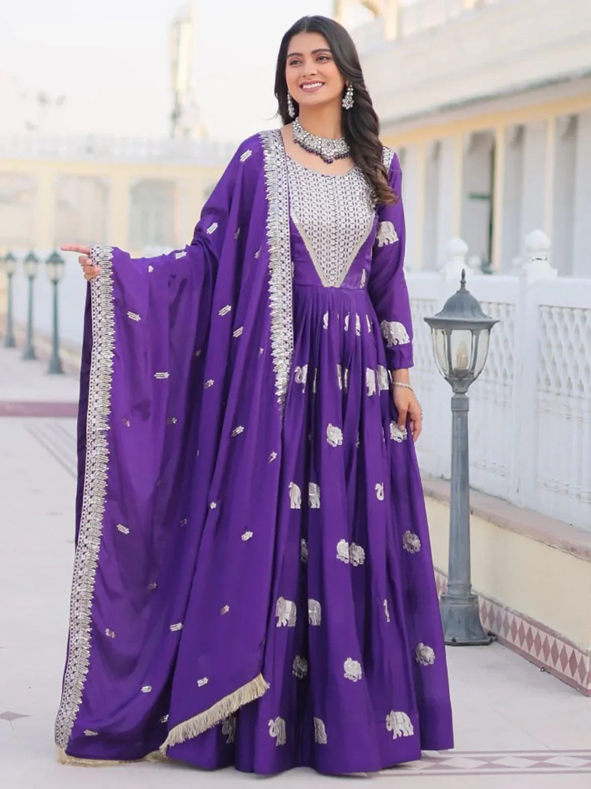 Woman wearing a purple embroidered ethnic gown with silver motifs and matching dupatta