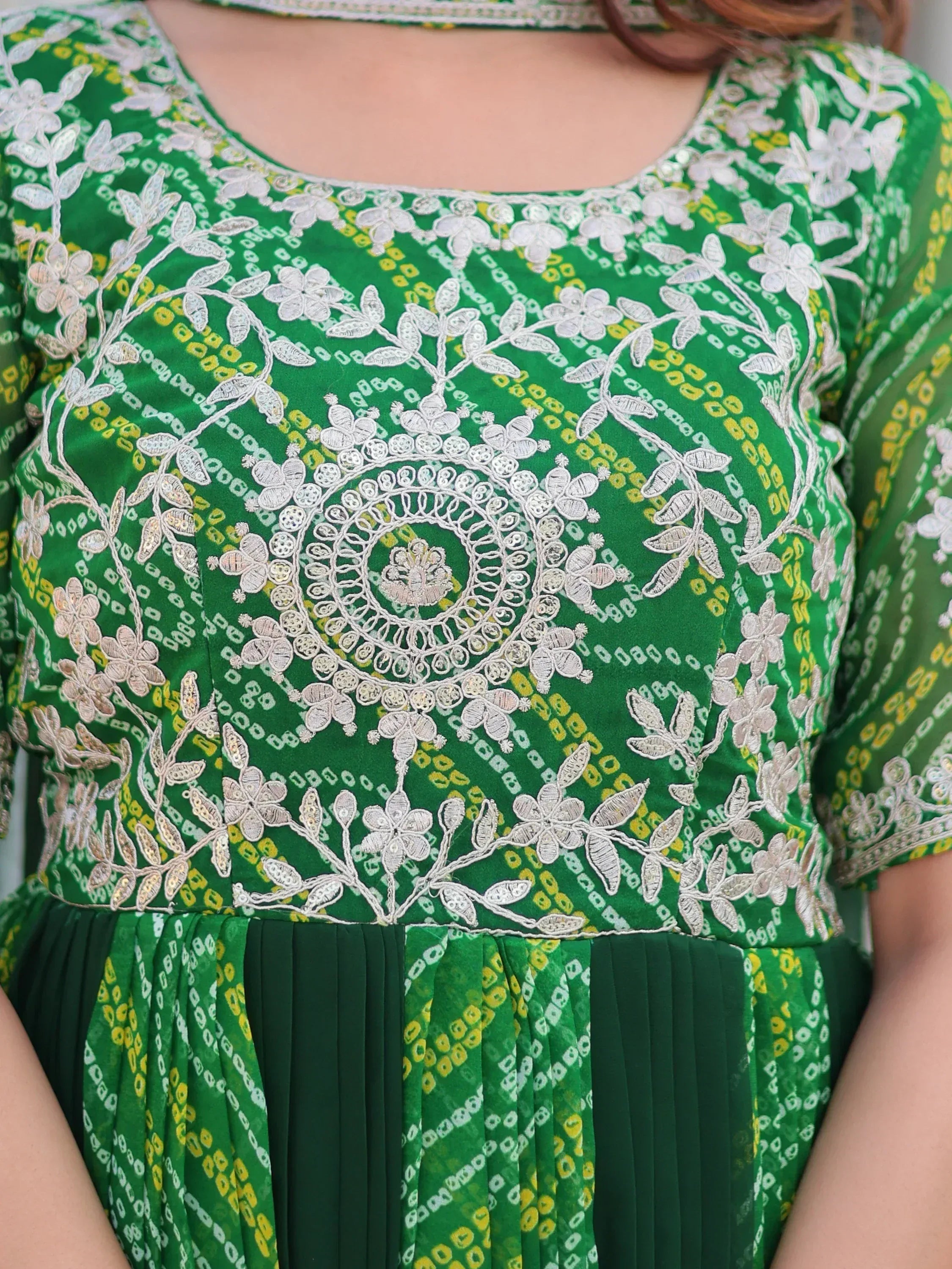 Green ethnic gown with white floral embroidery and pleated skirt, perfect for Indian occasions.