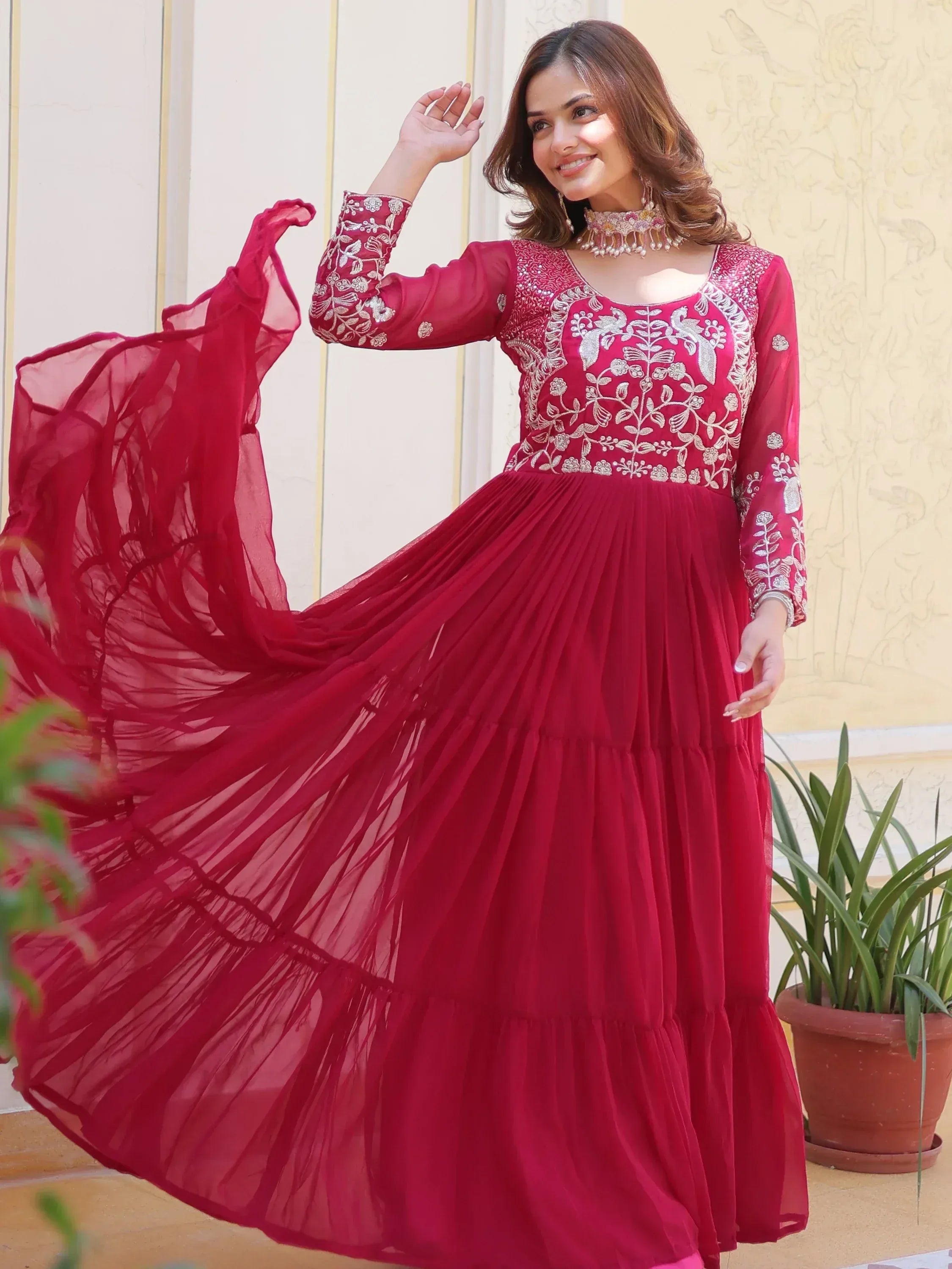 Woman in red embroidered ethnic gown with flowing skirt, perfect for Indian celebrations and festive occasions.