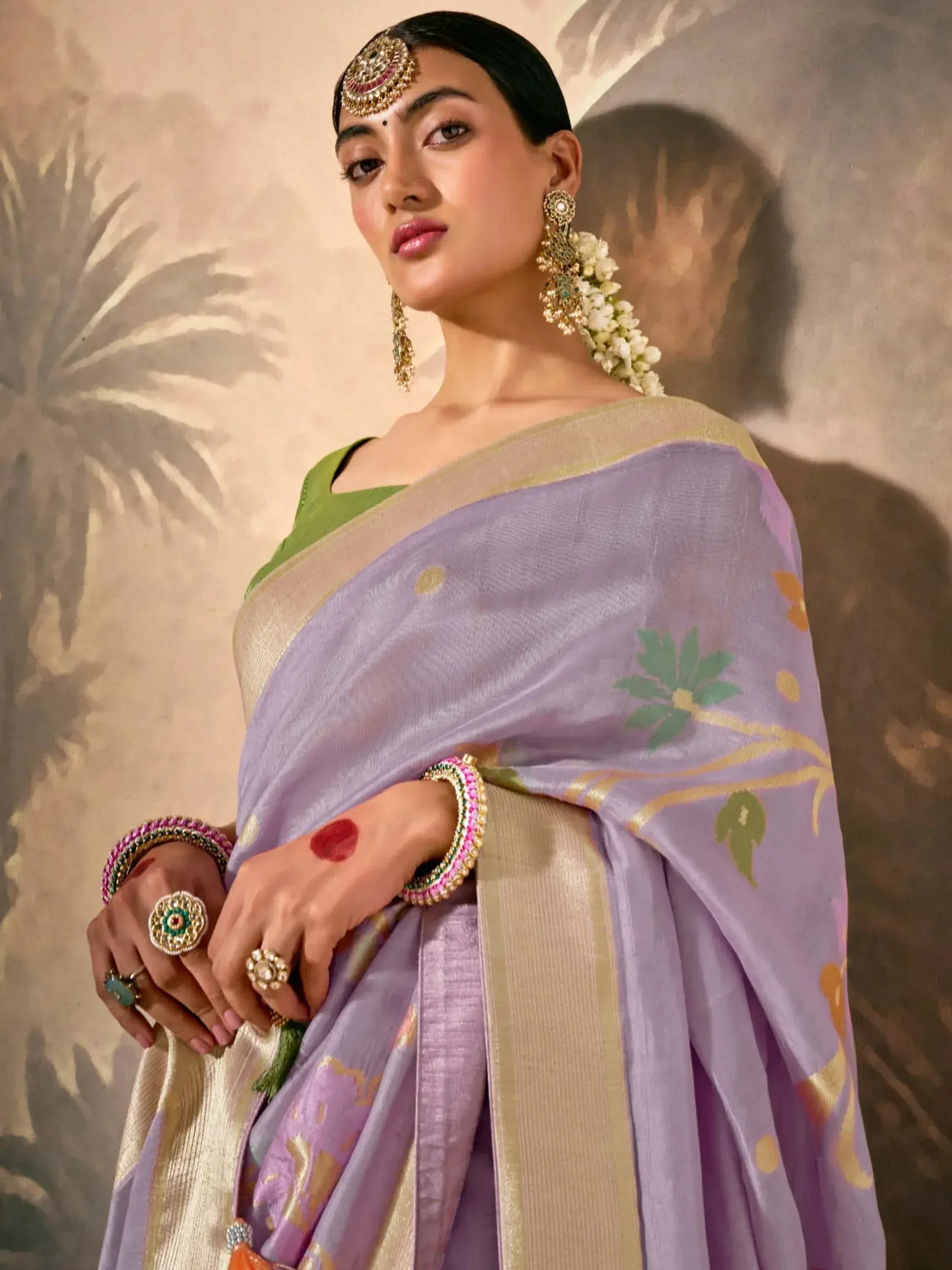 Woman in lavender floral saree with gold border, green blouse, and traditional Indian jewelry