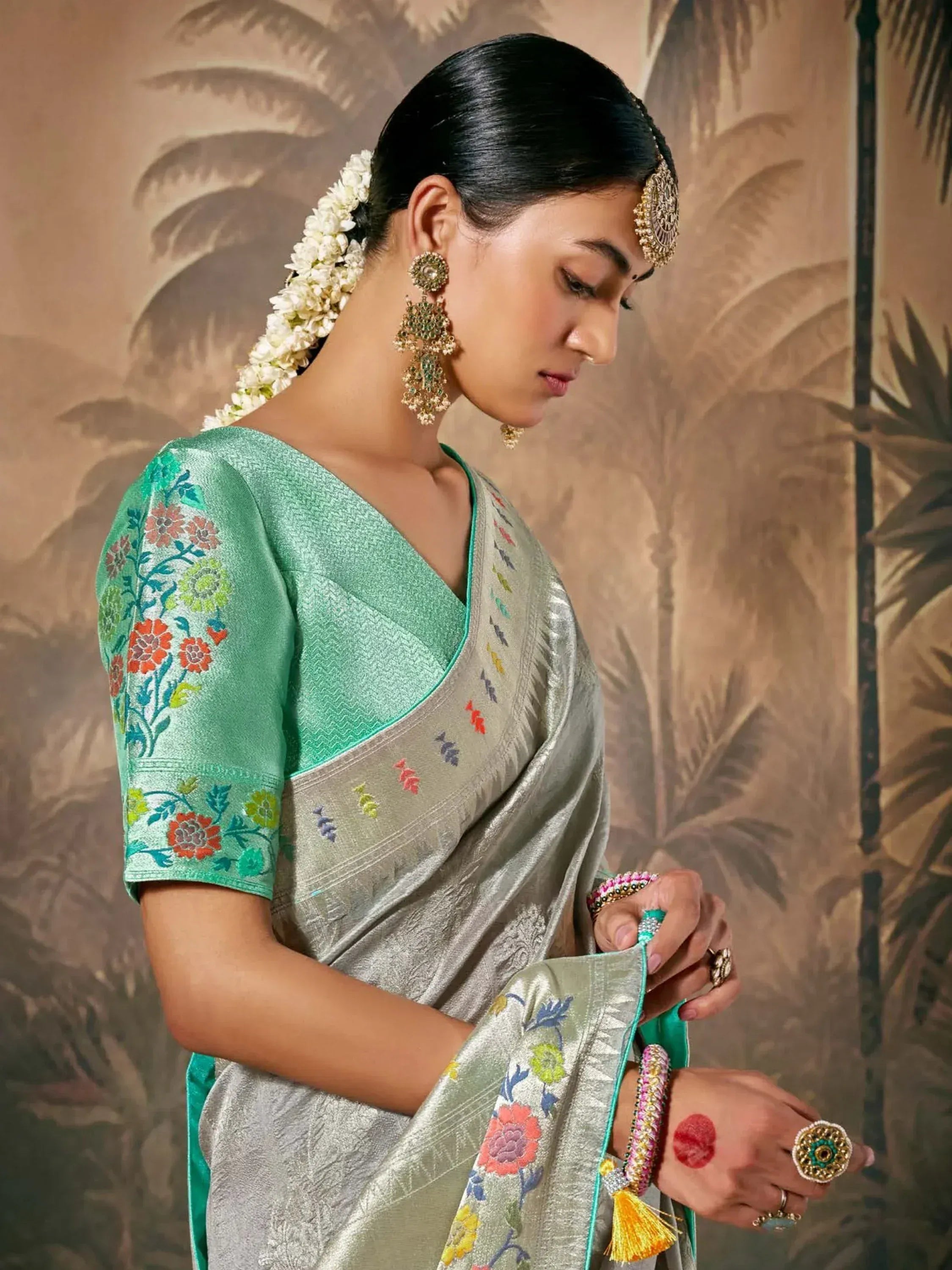 Woman in elegant silver saree with green floral blouse, traditional Indian ethnic wear