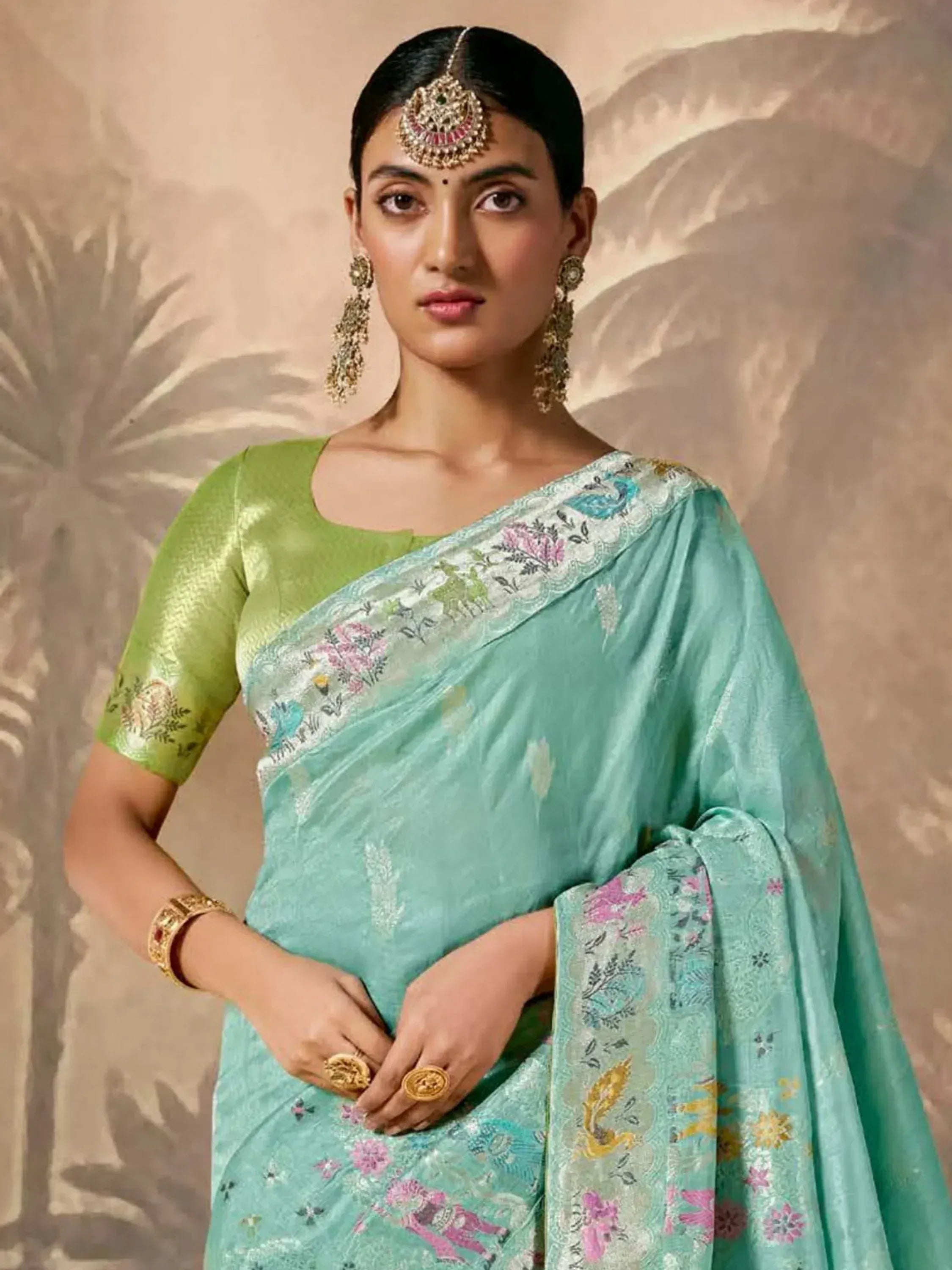 Woman in mint green floral saree with green blouse, traditional Indian ethnic wear, adorned with gold jewelry