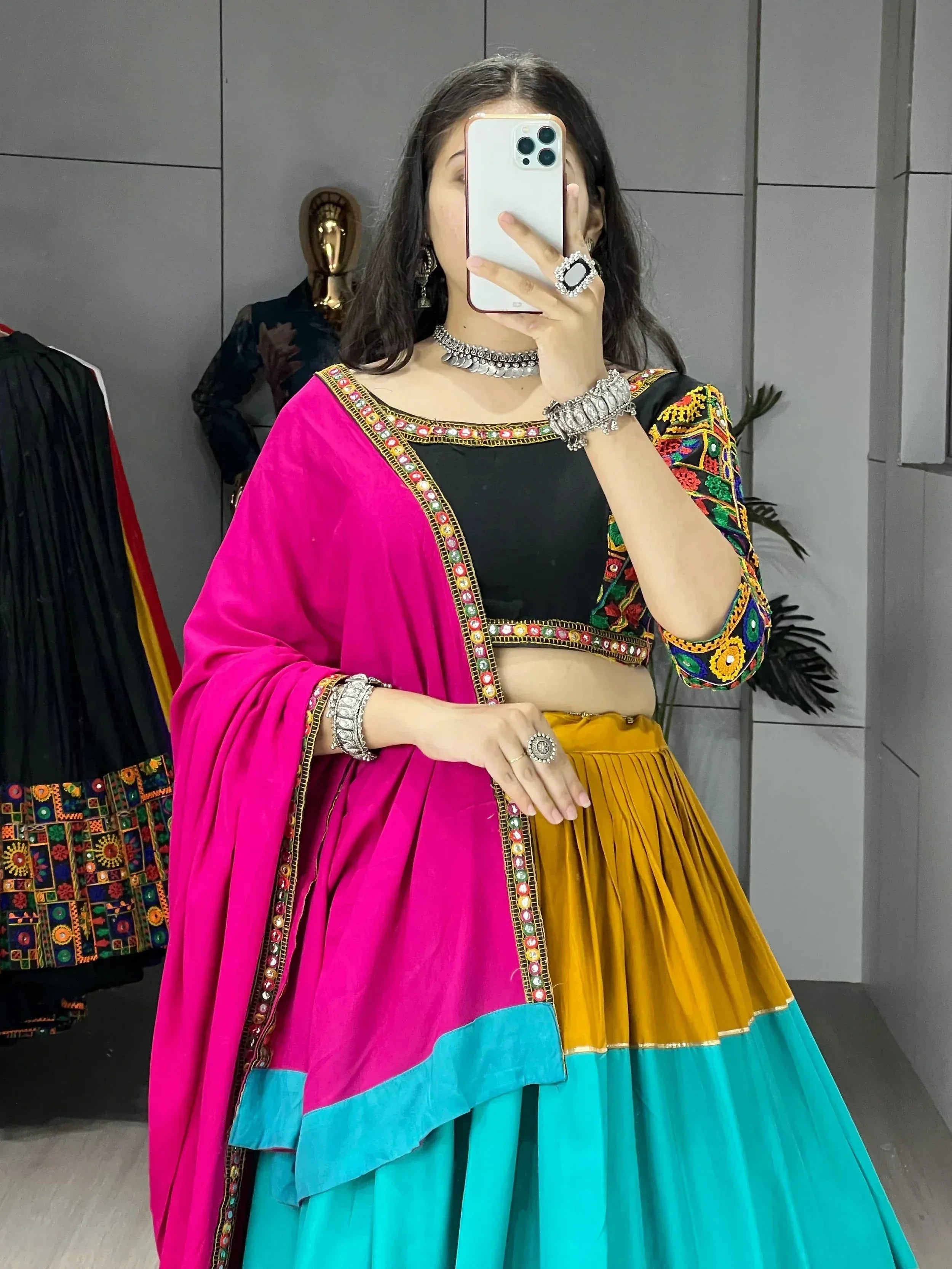 Woman in colorful Indian ethnic wear with embroidered black top, pink dupatta, and multi-color lehenga skirt