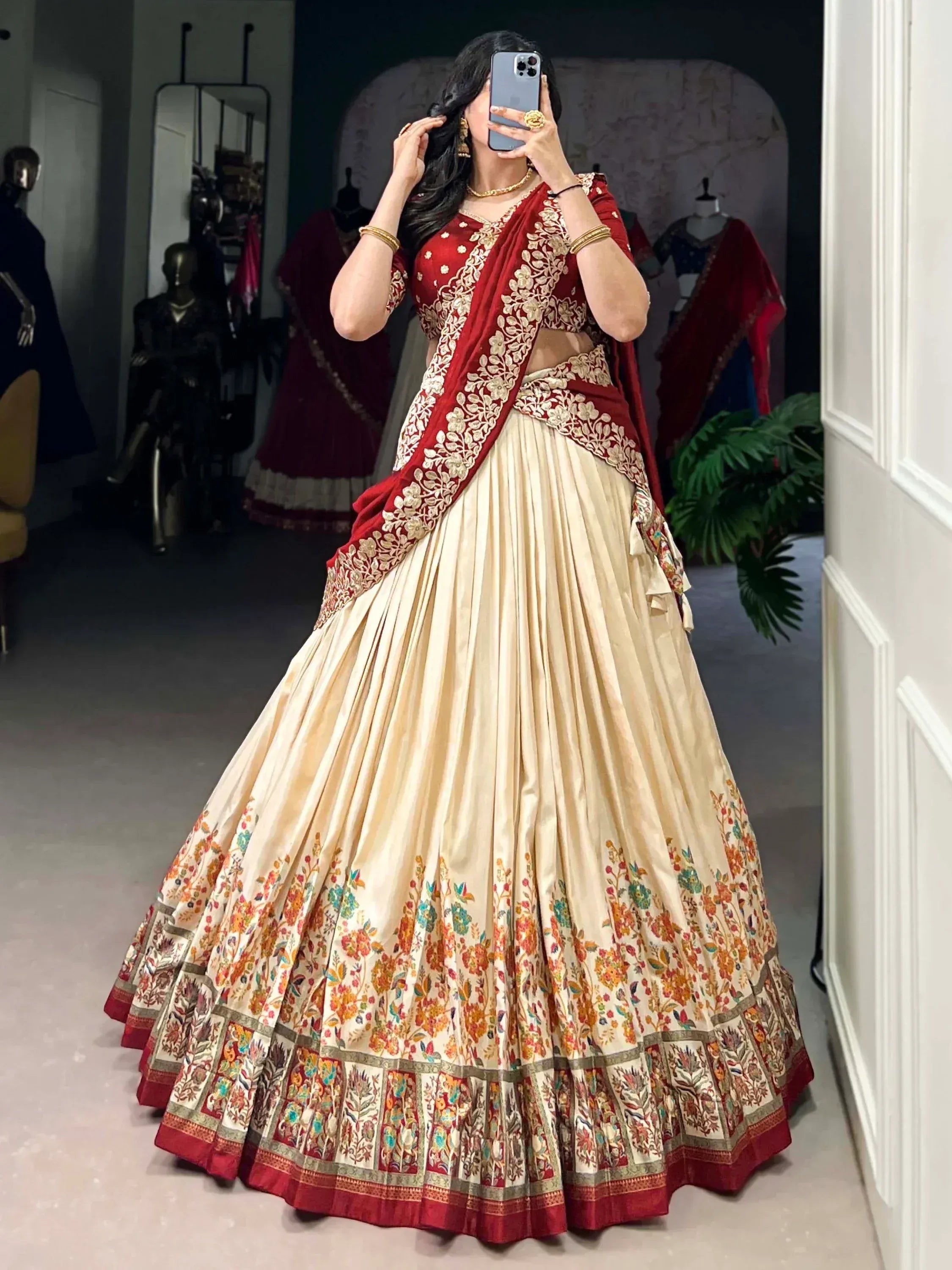 Woman in red and cream embroidered lehenga choli with floral border, perfect for Indian weddings and festive occasions.