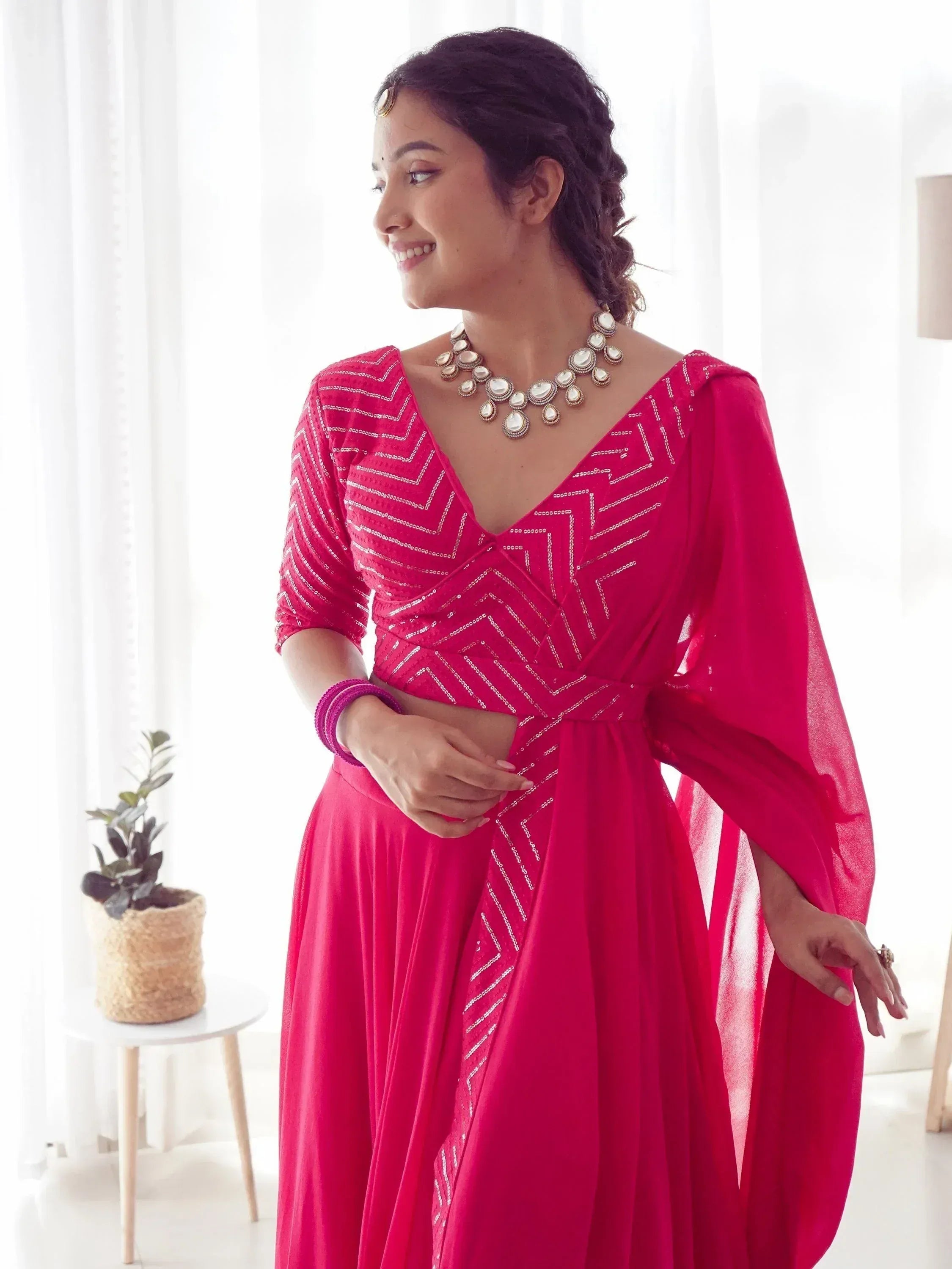 Woman in vibrant pink ethnic gown with silver chevron embroidery, perfect for Indian festive occasions