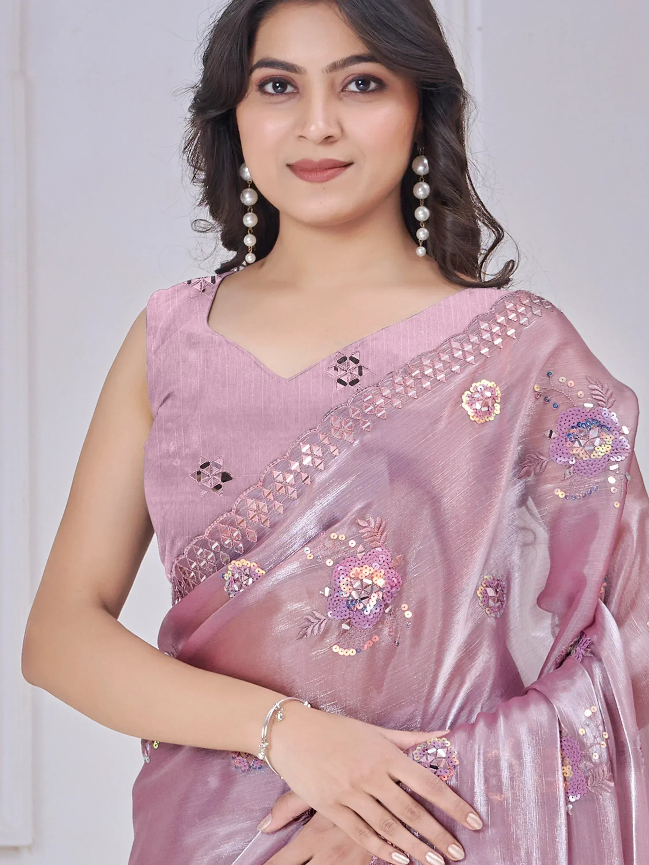 Pink designer saree with floral sequin embroidery and pearl earrings, perfect for ethnic occasions