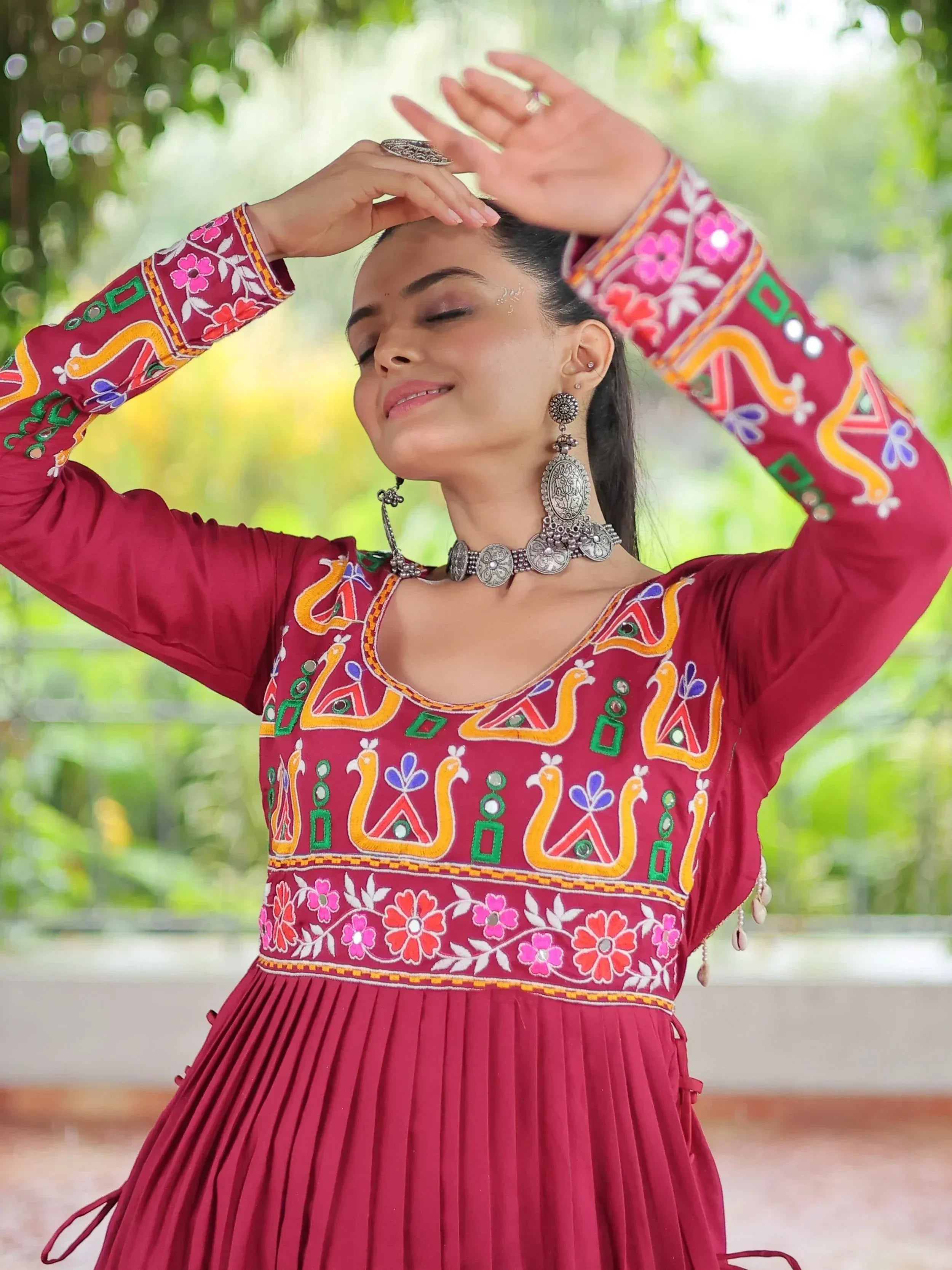 Maroon embroidered ethnic gown with floral and mirror work, paired with silver jewelry for festive occasions