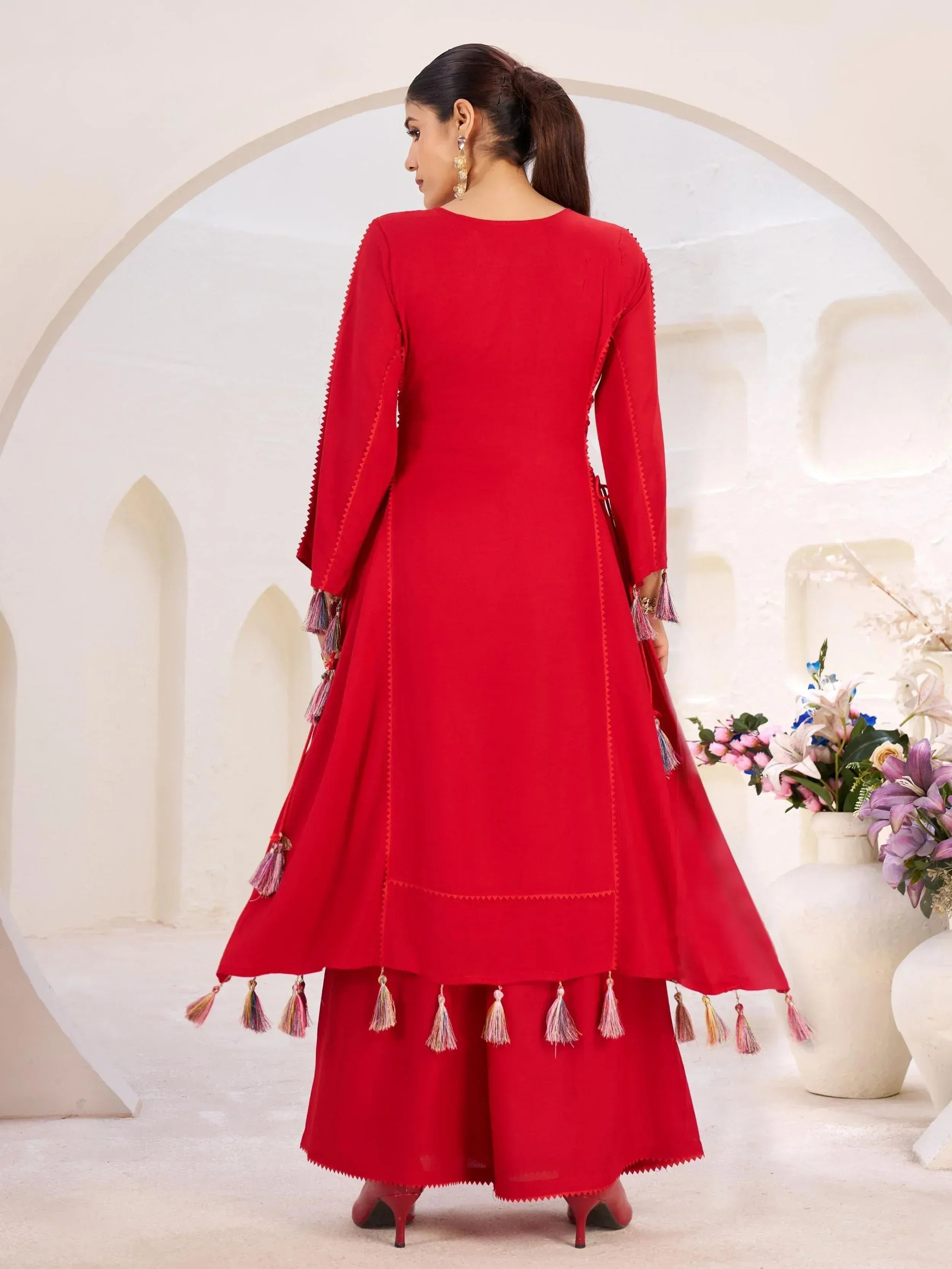 Red ethnic anarkali suit with tassel detailing, perfect for Indian occasions and festive wear.