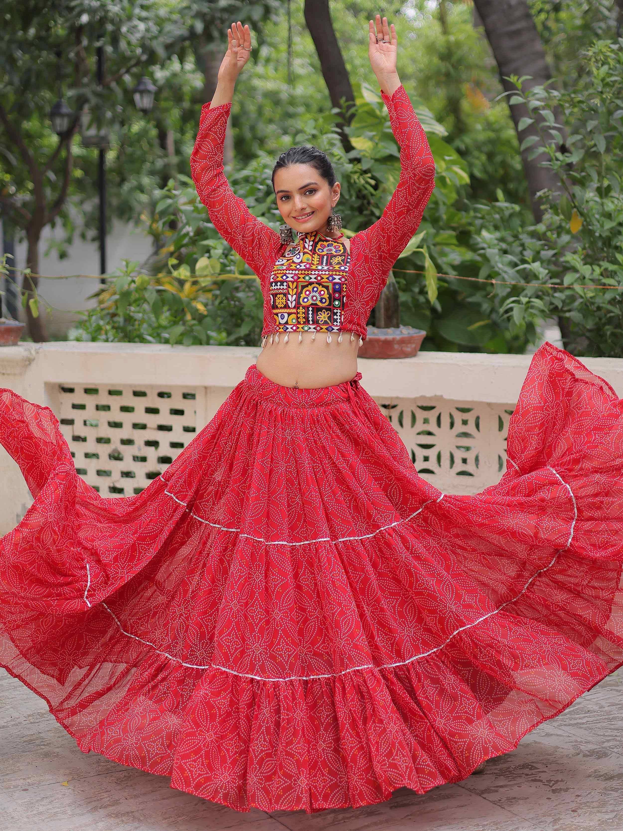 Woman in red ethnic lehenga choli with mirror work, dancing outdoors
