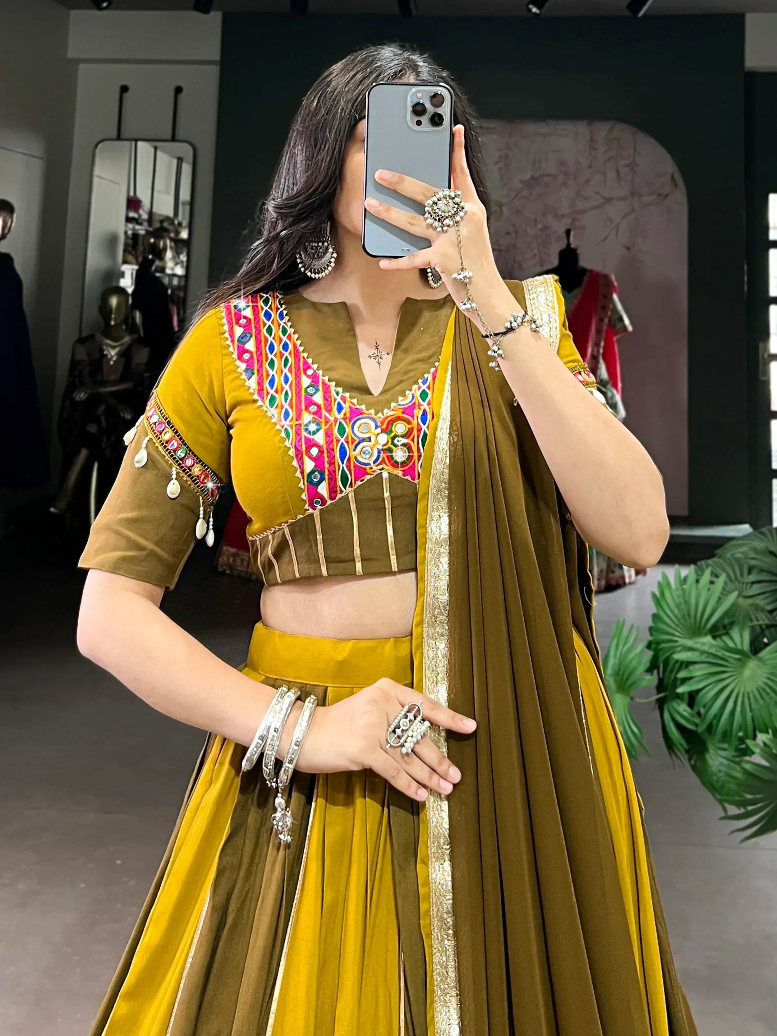 Woman in mustard yellow and olive green ethnic lehenga choli with mirror work, perfect for Indian weddings or festive occasions.