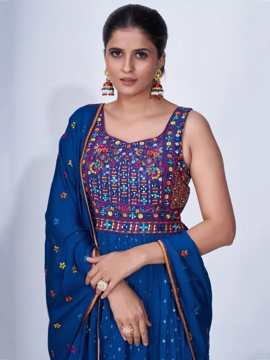 Woman in blue embroidered ethnic gown with matching dupatta, statement earrings, and rings