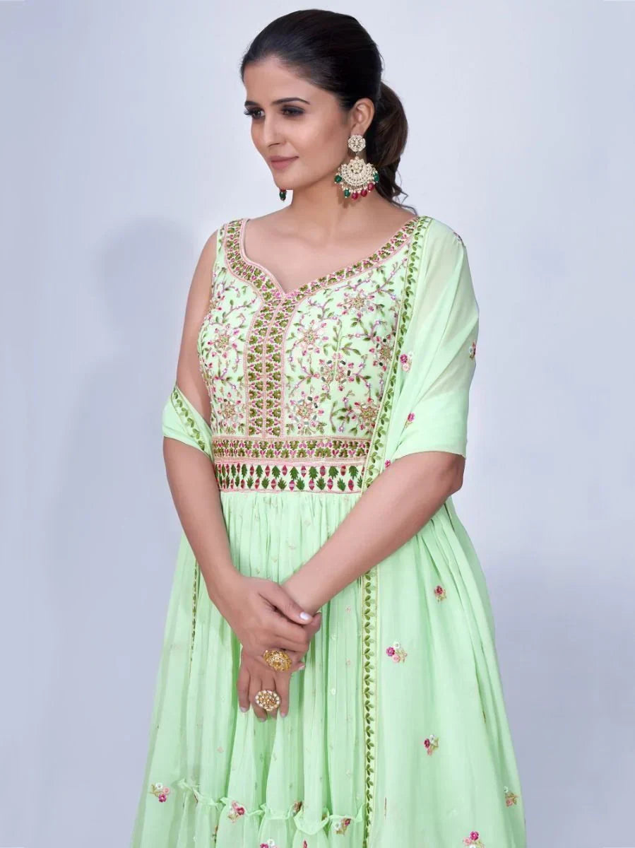 Woman wearing light green embroidered Anarkali suit with floral patterns and statement earrings
