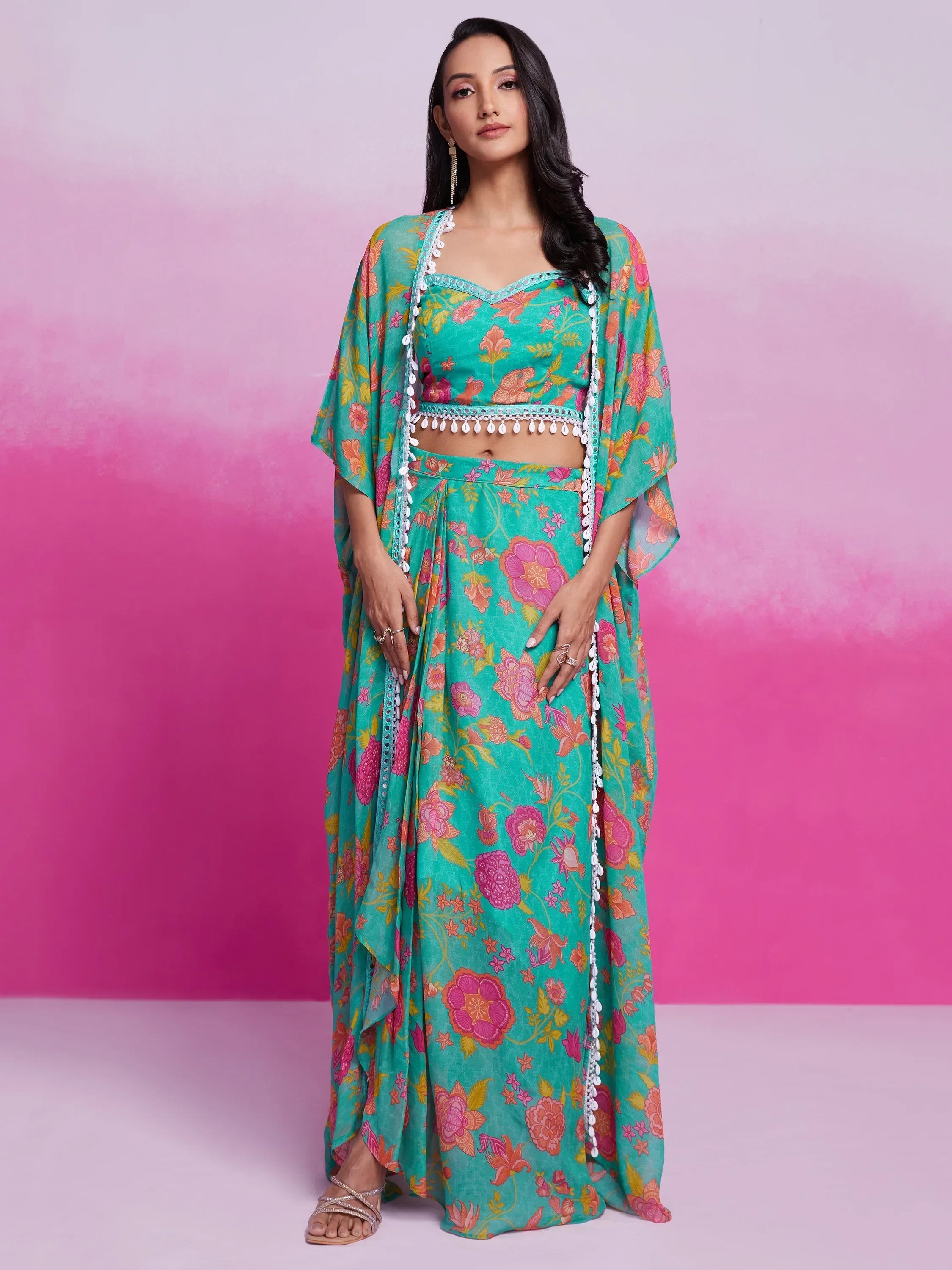 Woman wearing teal floral printed lehenga choli with dupatta, standing against pink background