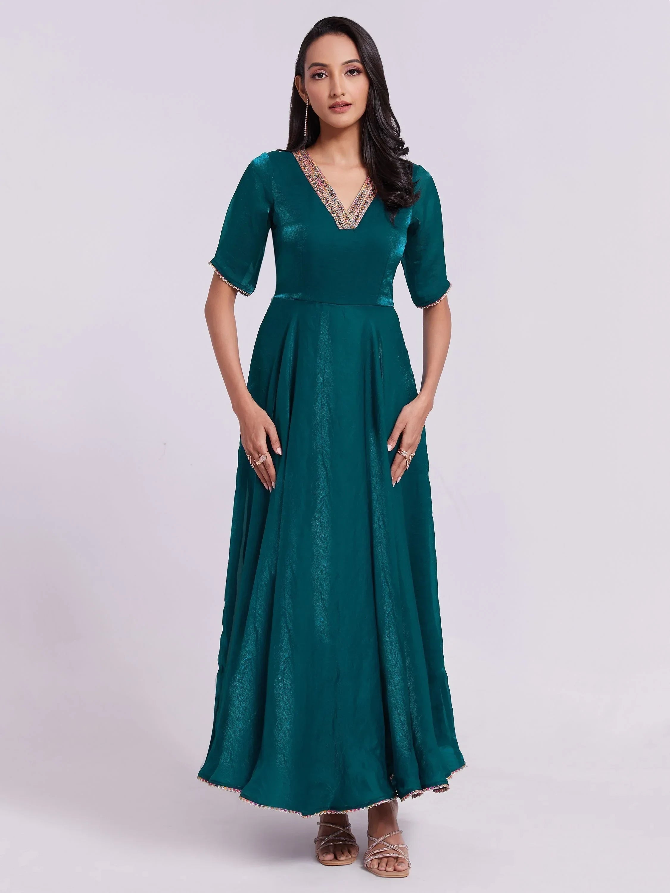 Woman wearing teal silk ethnic gown with half sleeves and embellished V-neckline