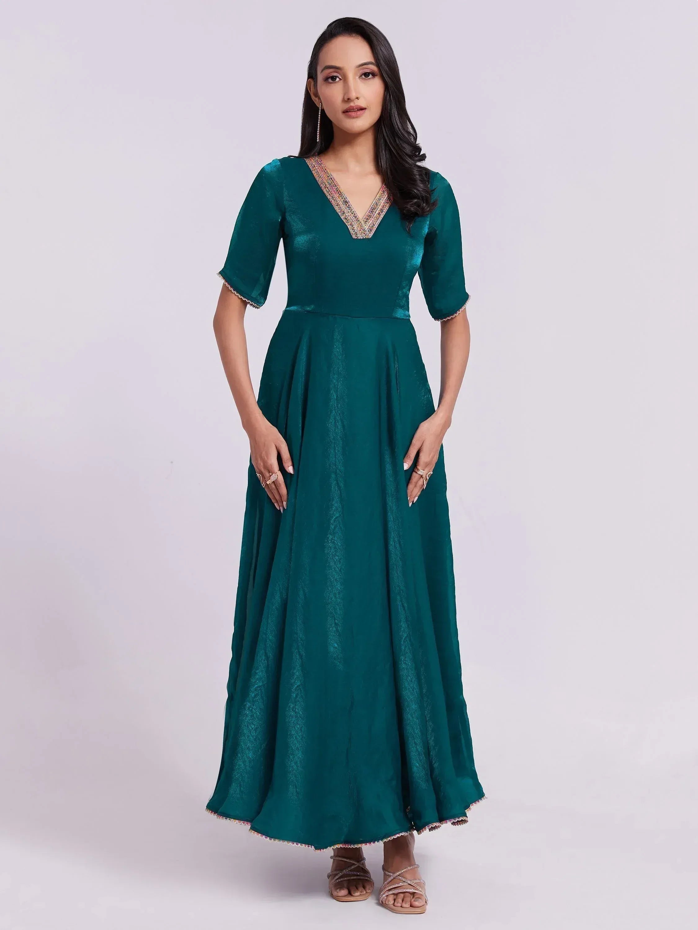 Woman wearing teal silk ethnic gown with half sleeves and embellished V-neckline