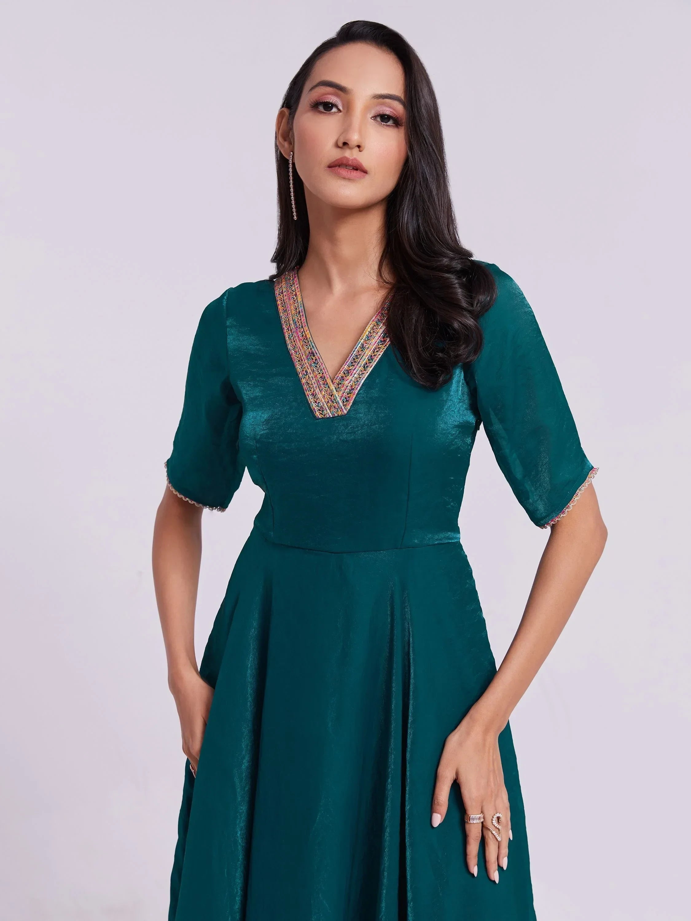 Woman in teal ethnic gown with V-neck, embellished neckline, and half sleeves