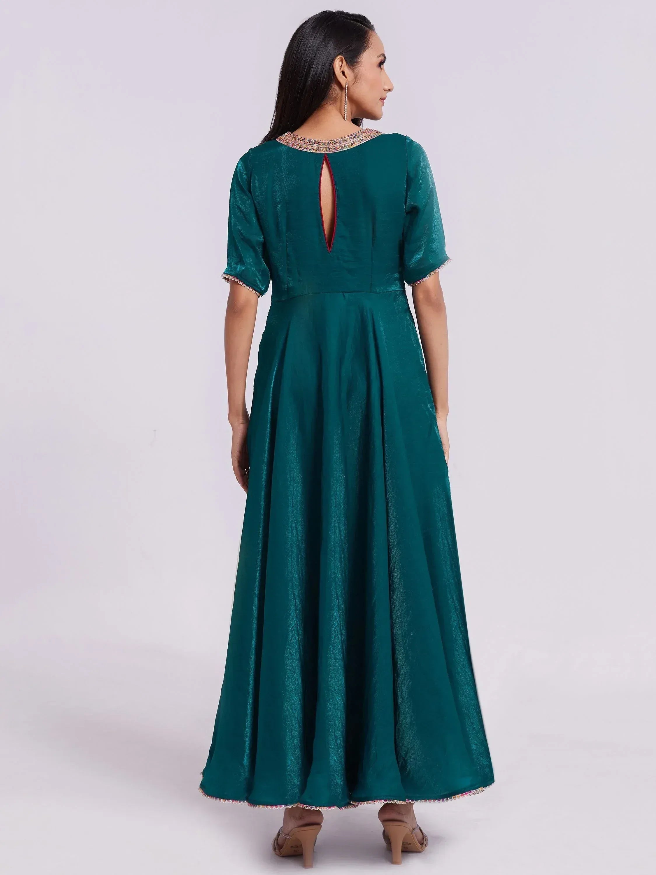Woman wearing teal silk ethnic gown with short sleeves and embellished neckline, back view