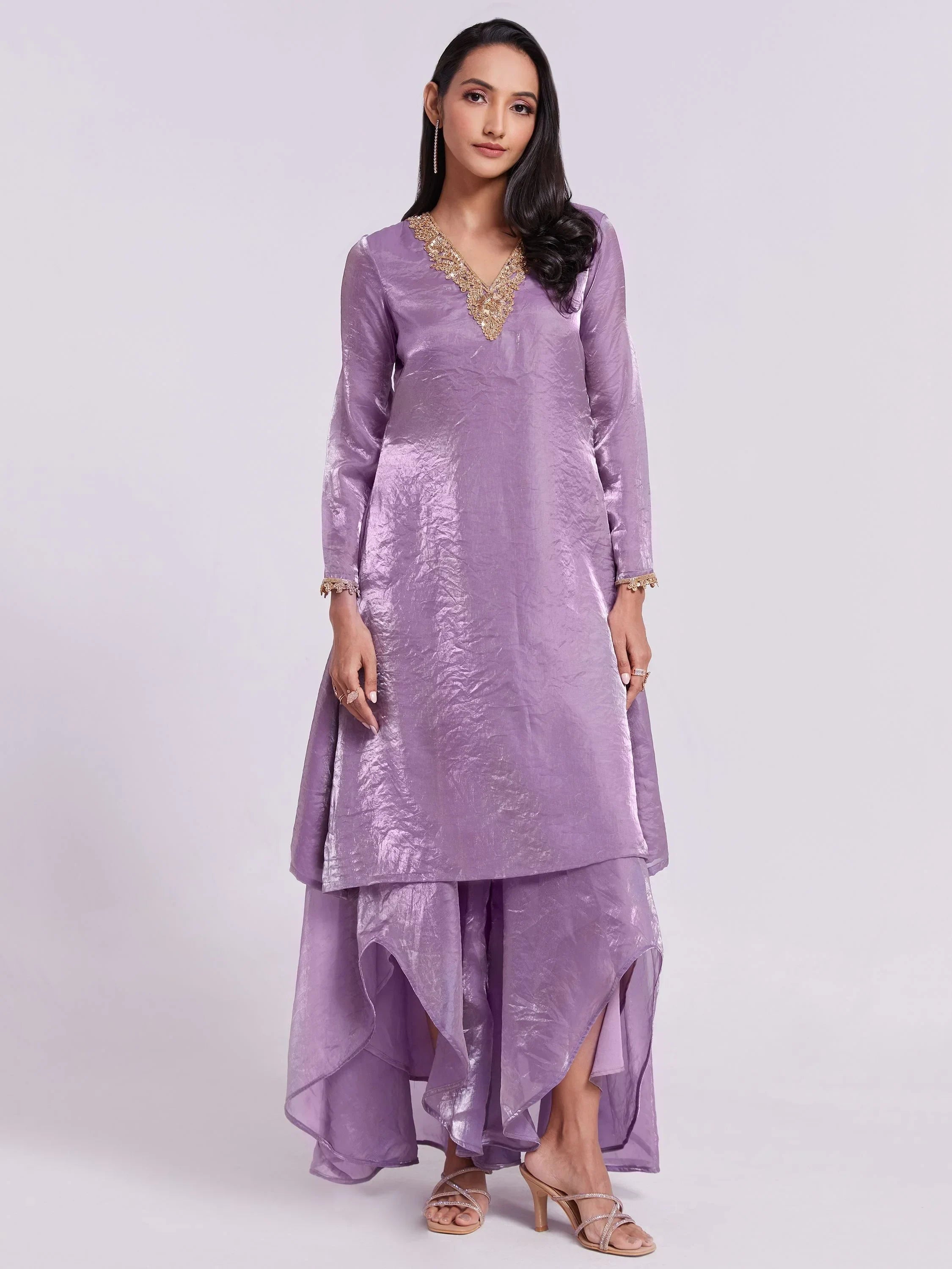 Woman wearing a purple silk ethnic gown with gold embroidered V-neck and layered hem