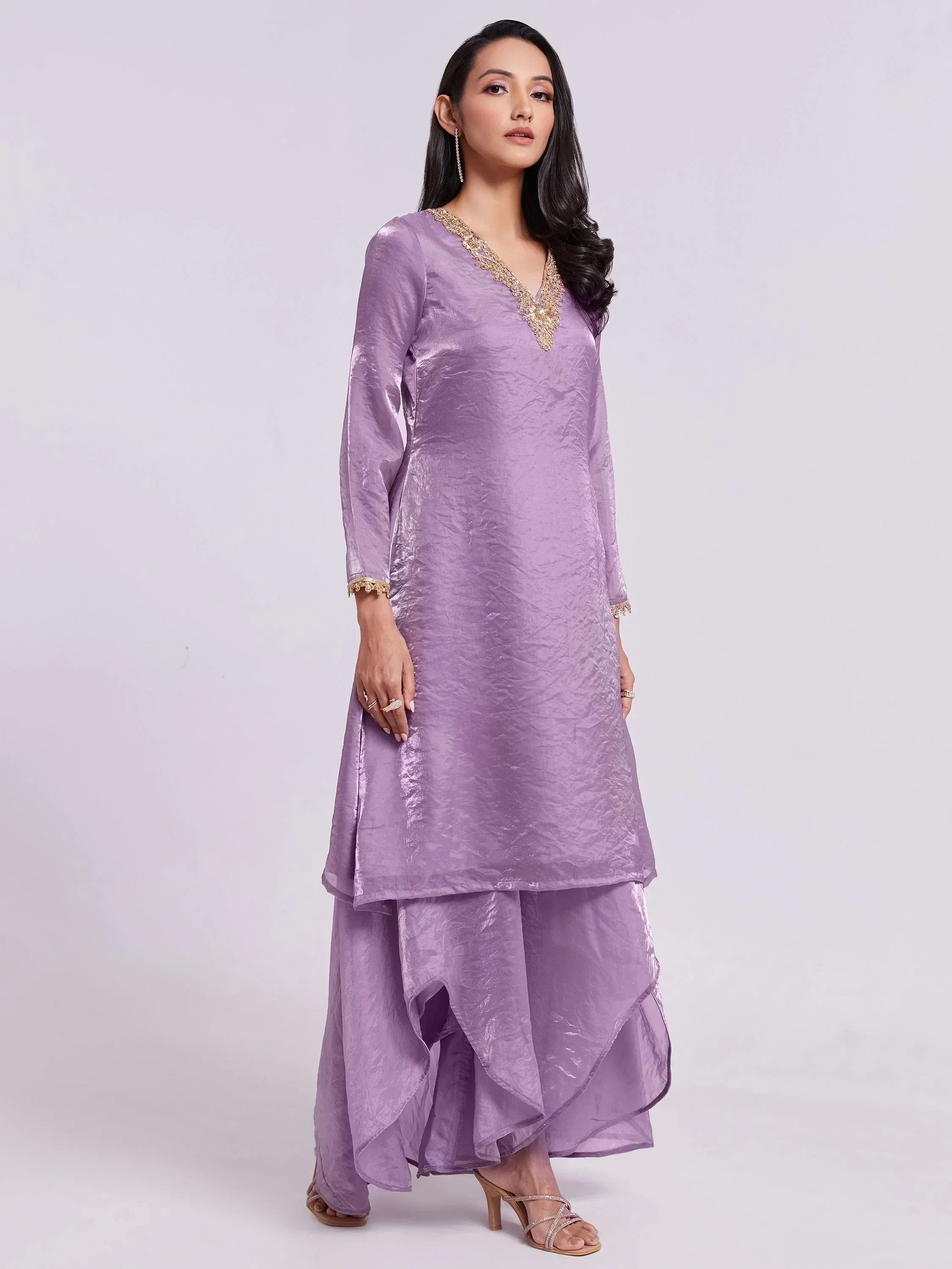 Woman wearing a lavender silk kurta set with gold embroidery and flared palazzo pants