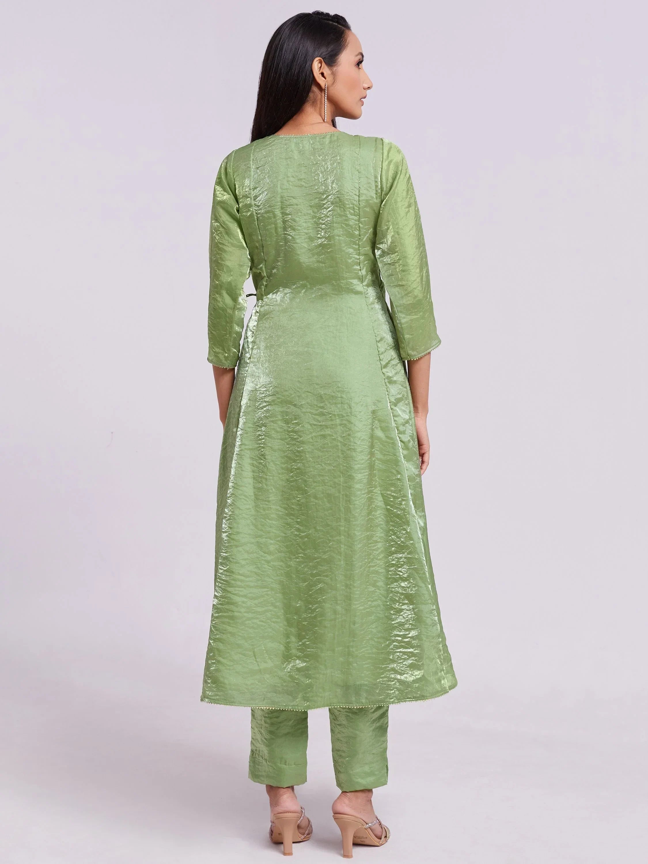 Woman wearing light green ethnic kurta and straight pants, standing in a studio