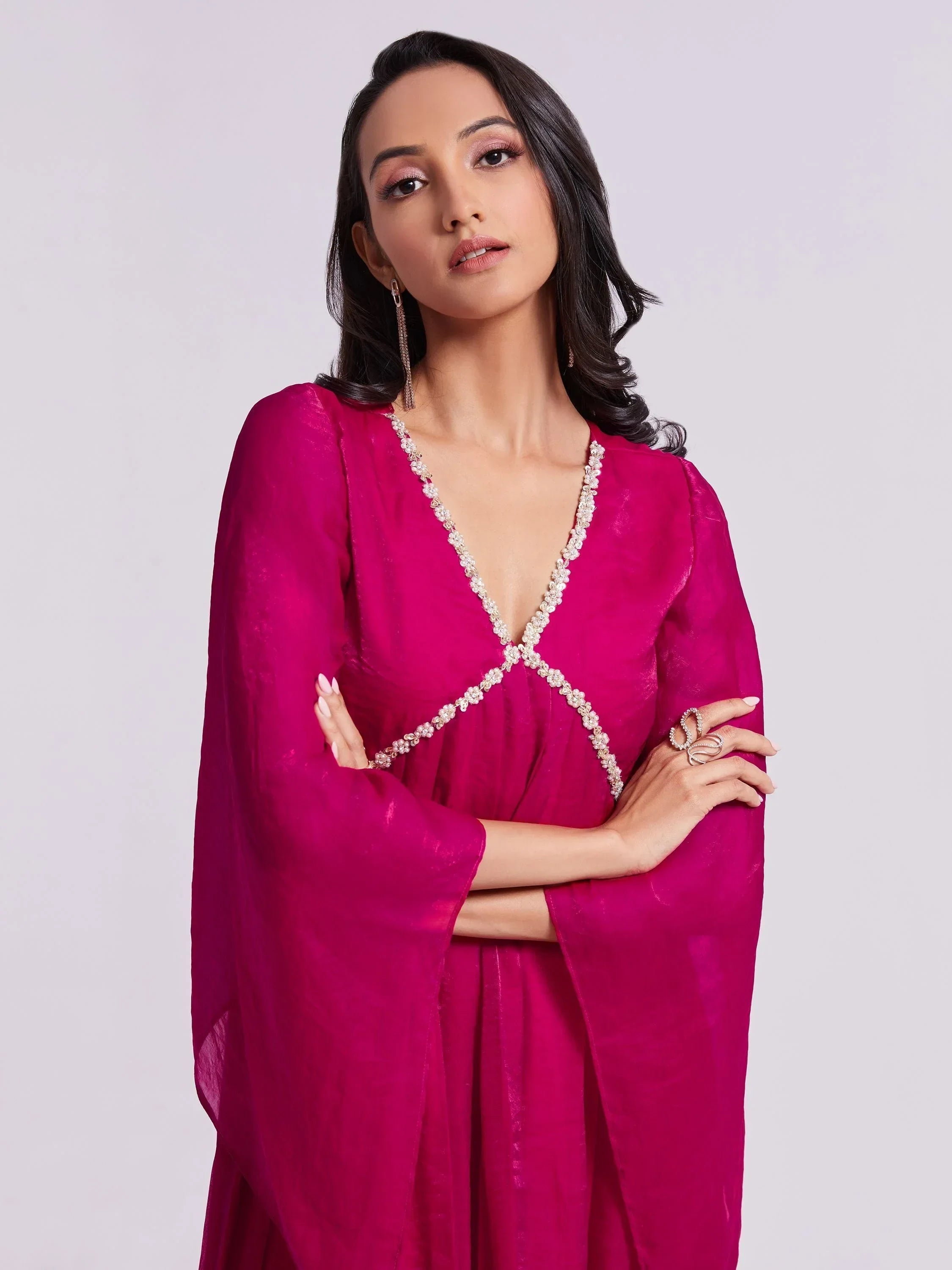 Woman wearing magenta ethnic gown with flared sleeves and embellished neckline