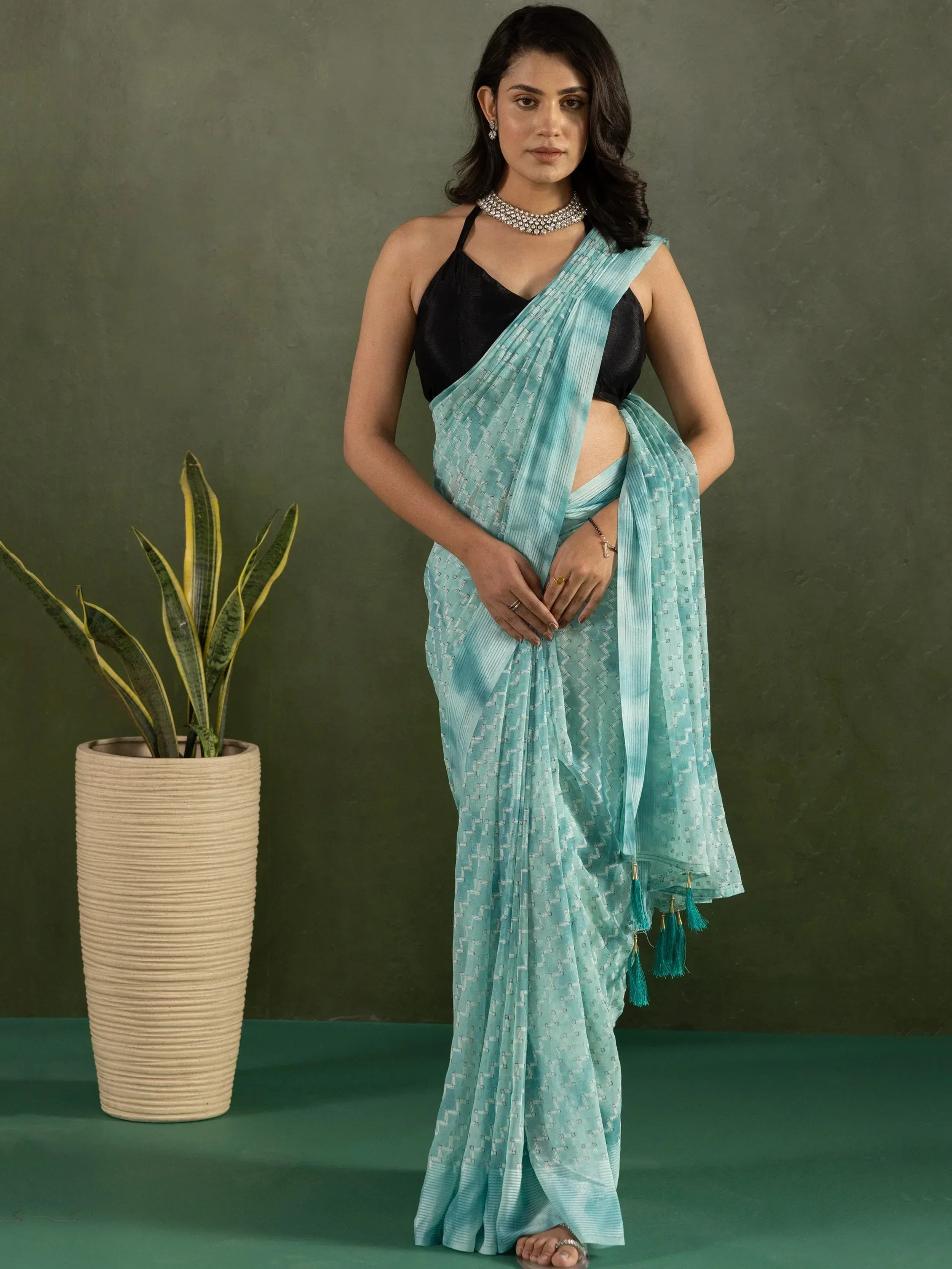 Woman in light blue printed saree with black blouse and tassels, styled for ethnic wear occasions