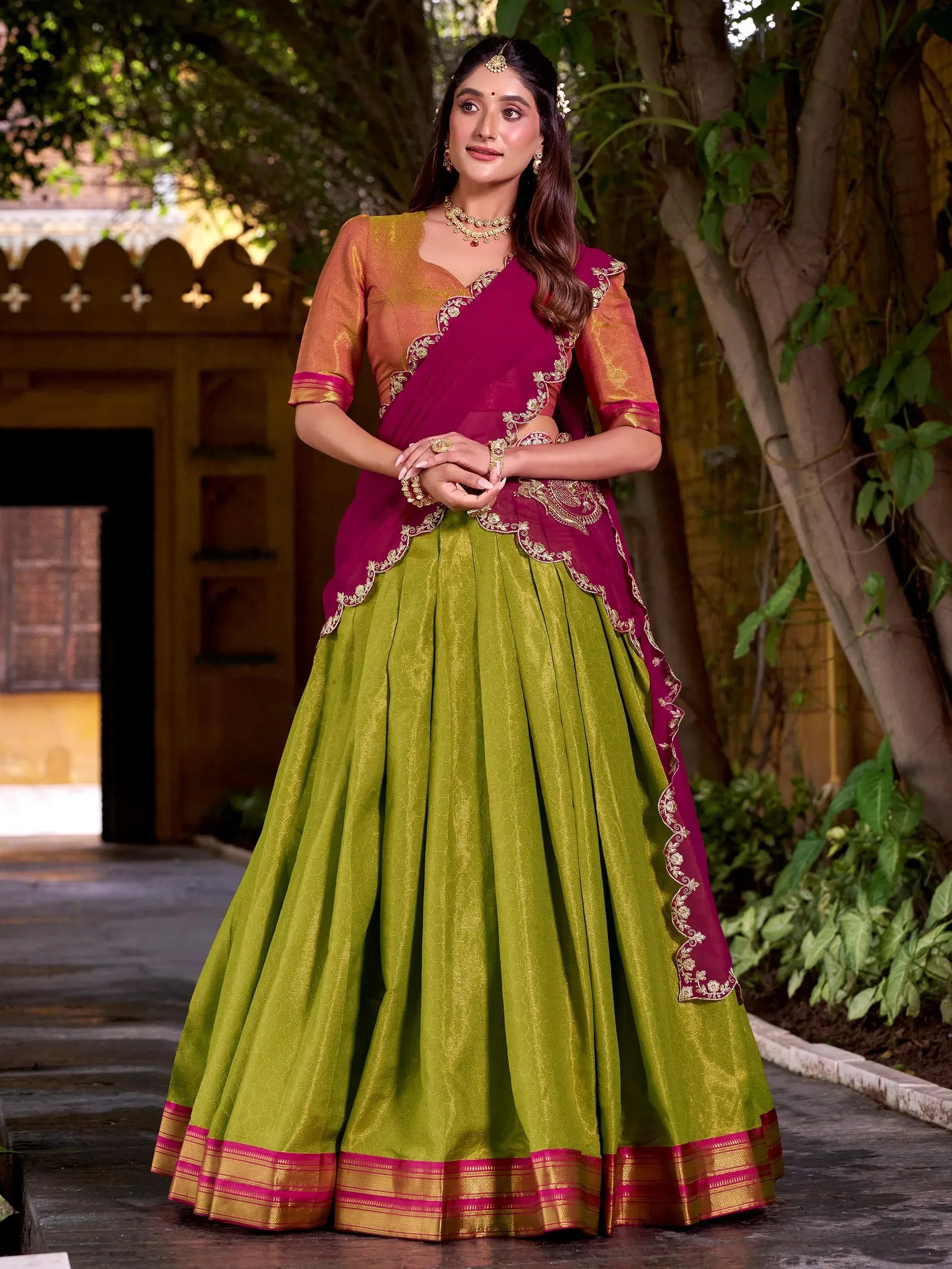 Woman in vibrant green and maroon designer lehenga choli with gold embroidery, perfect for Indian ethnic wear occasions