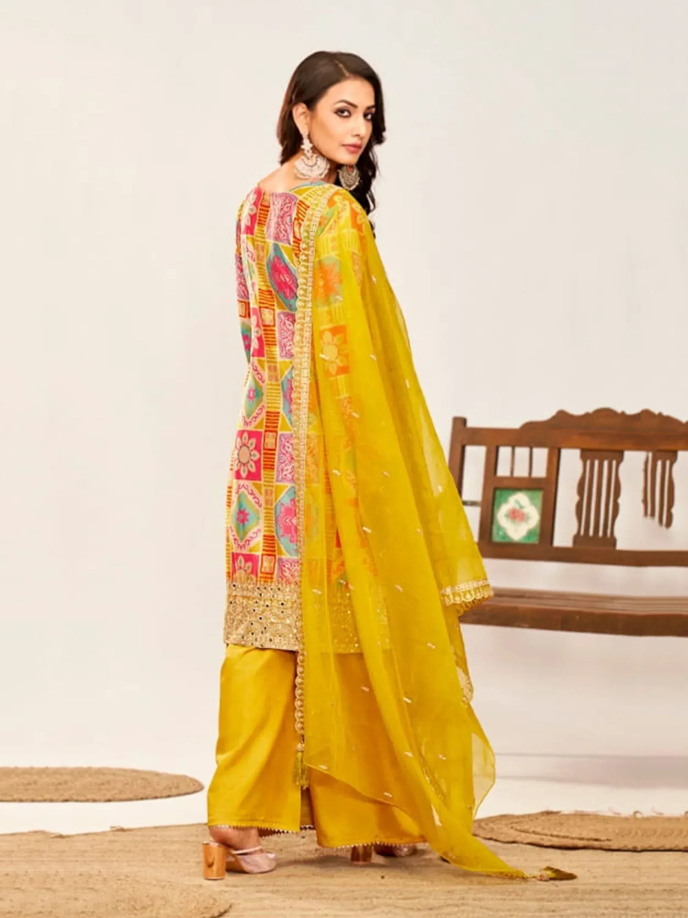 Vibrant yellow ethnic salwar kameez with colorful patchwork and sheer dupatta, perfect for festive occasions.