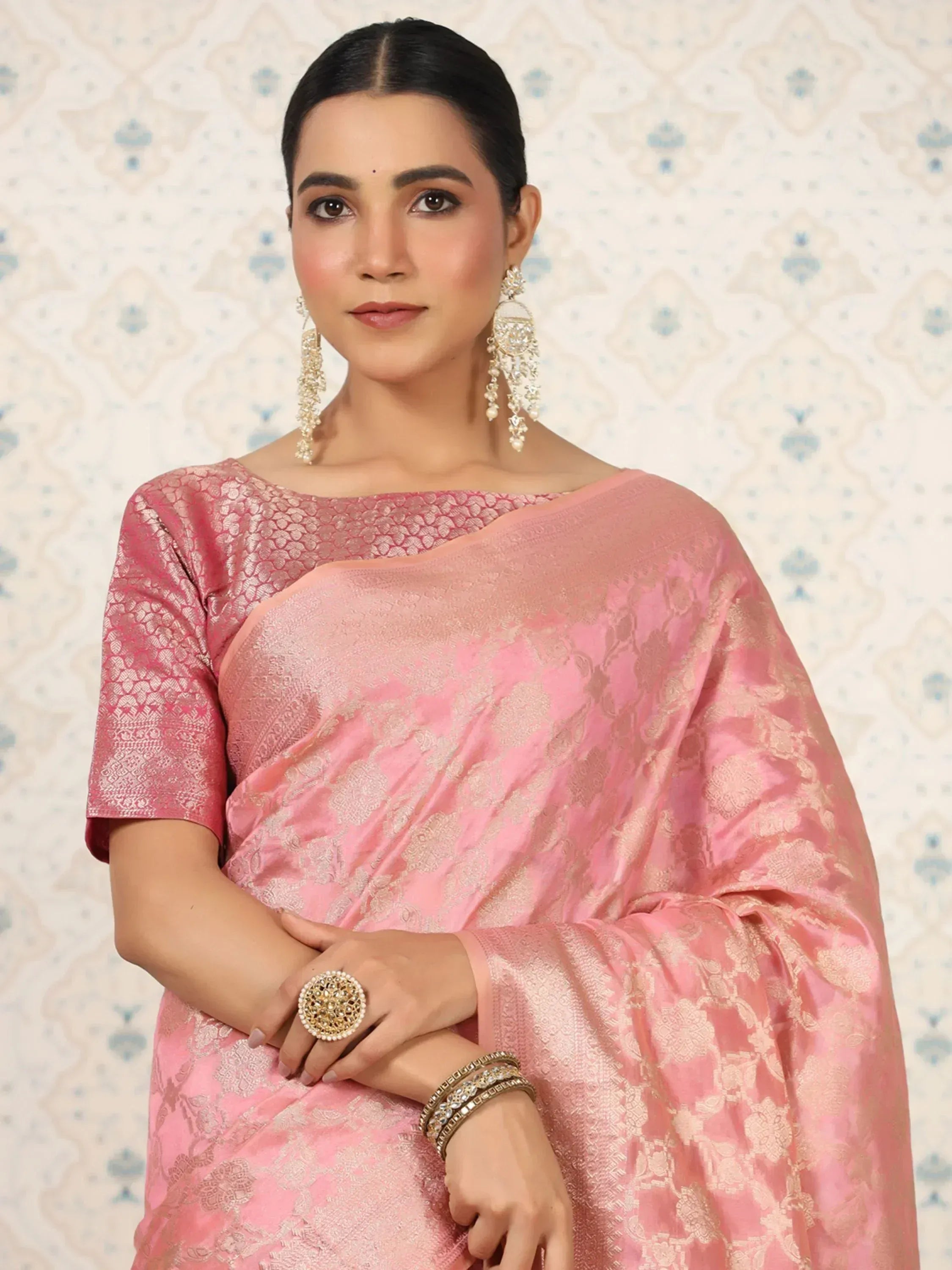 Pink designer saree with gold floral embroidery, paired with statement earrings and ring for ethnic wear