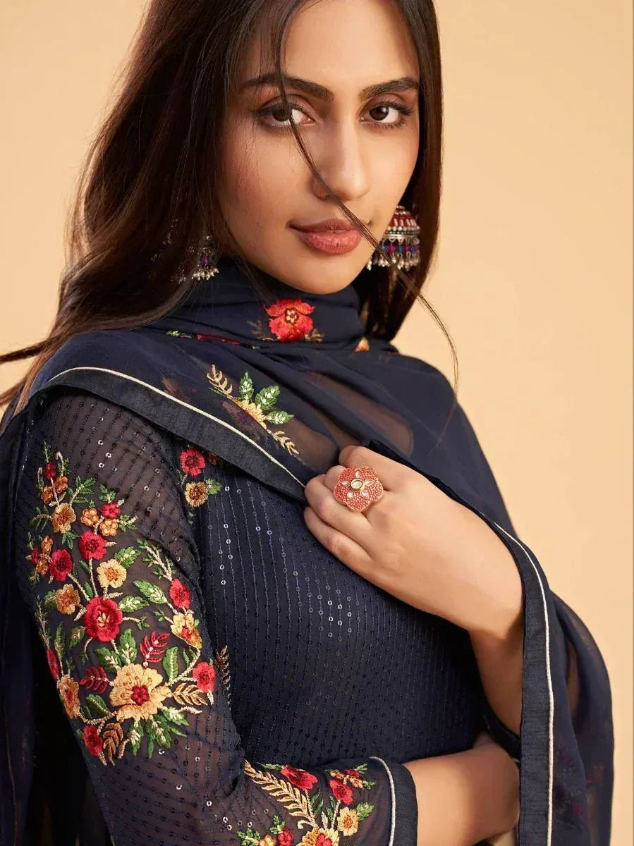 Navy blue embroidered ethnic gown with floral detailing and sheer sleeves, styled with statement earrings.