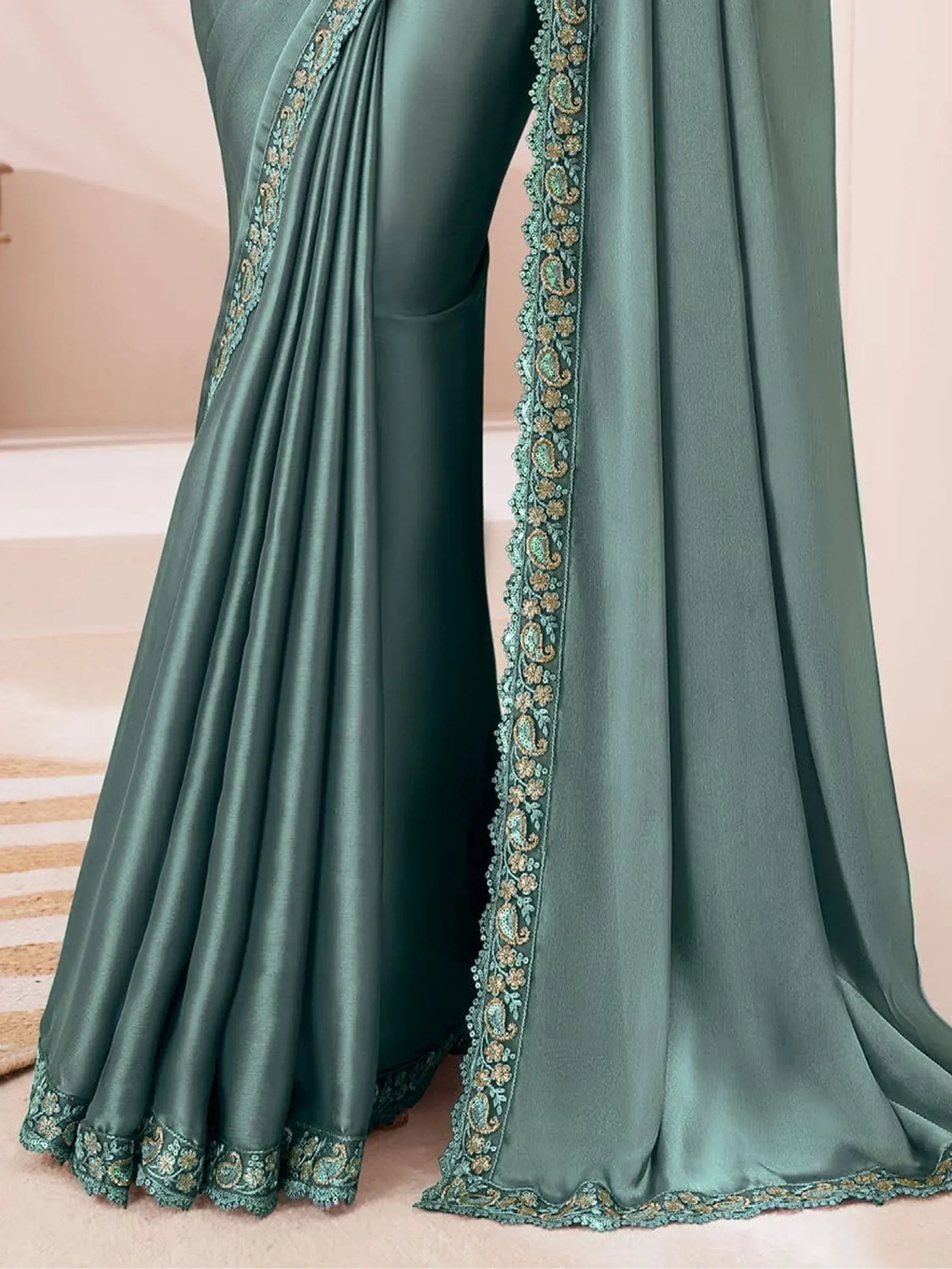 Emerald green satin saree with intricate paisley and floral embroidery, perfect for Indian ethnic wear.