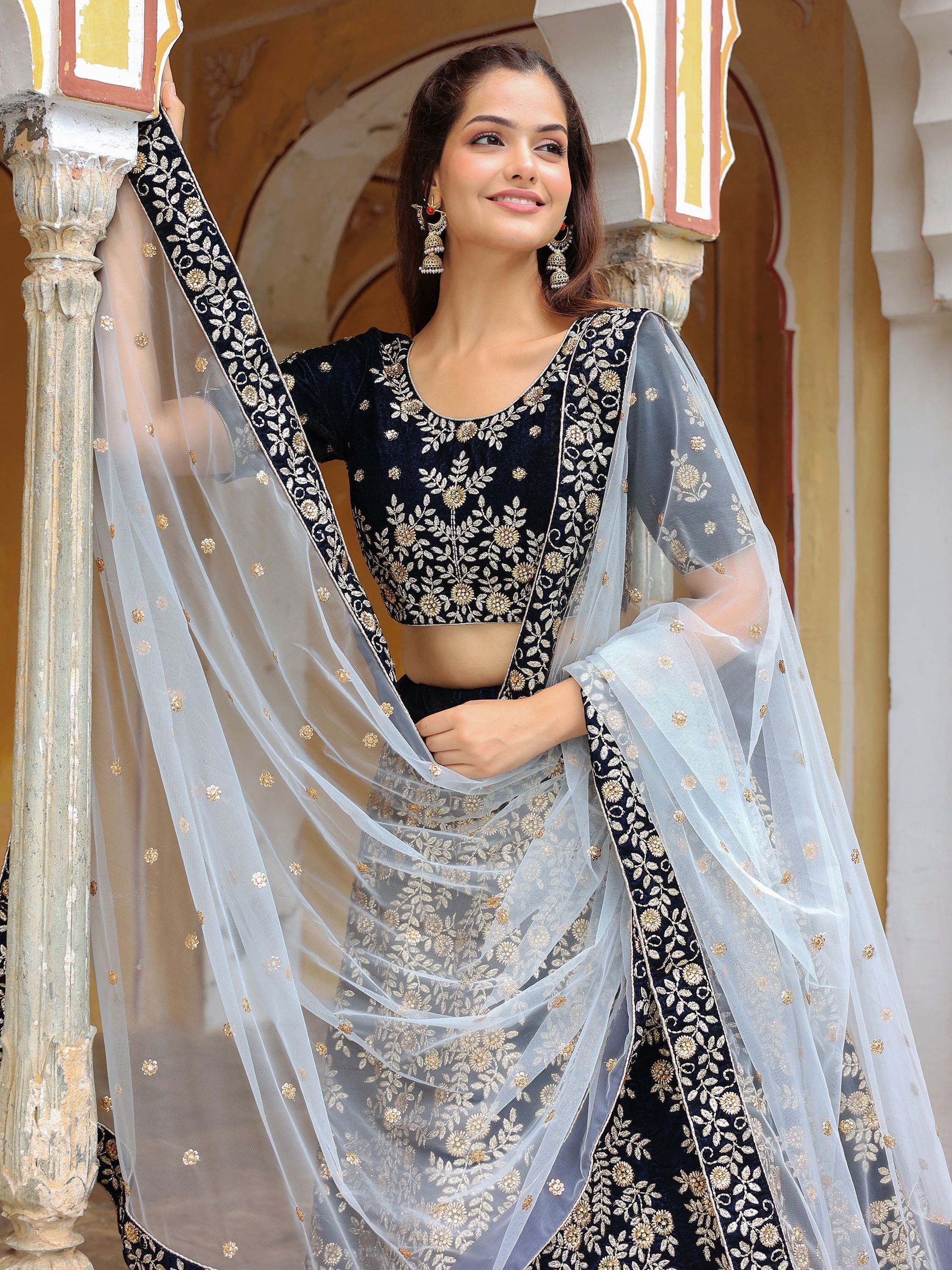 Elegant navy blue velvet lehenga choli with gold floral embroidery and sheer dupatta, perfect for Indian ethnic occasions.