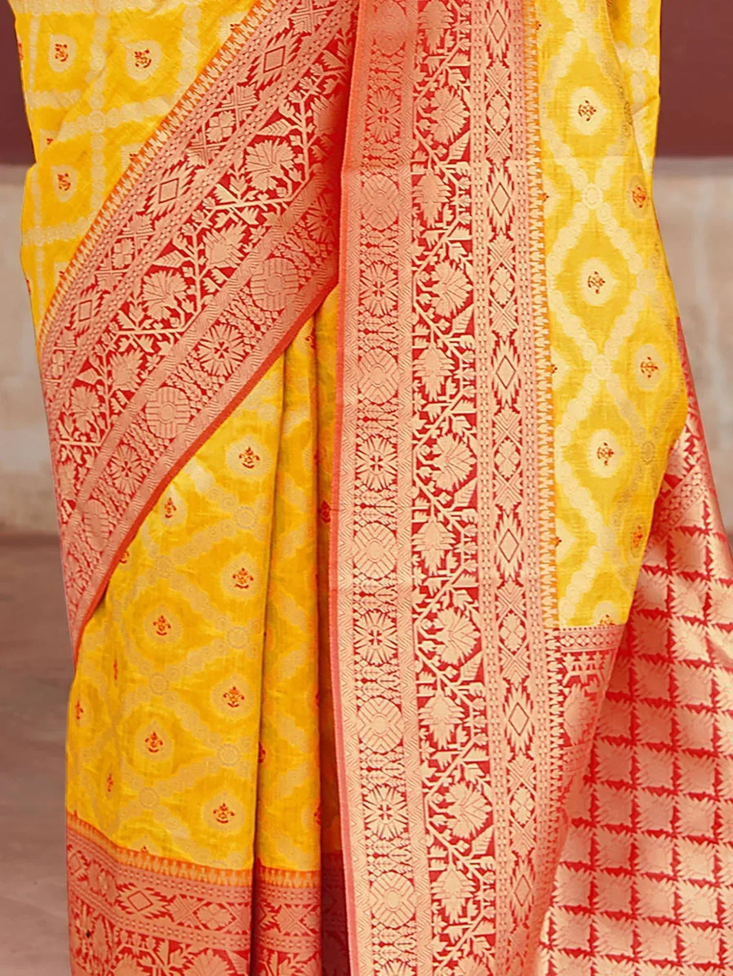 Yellow and coral ethnic saree with intricate floral and geometric woven border patterns