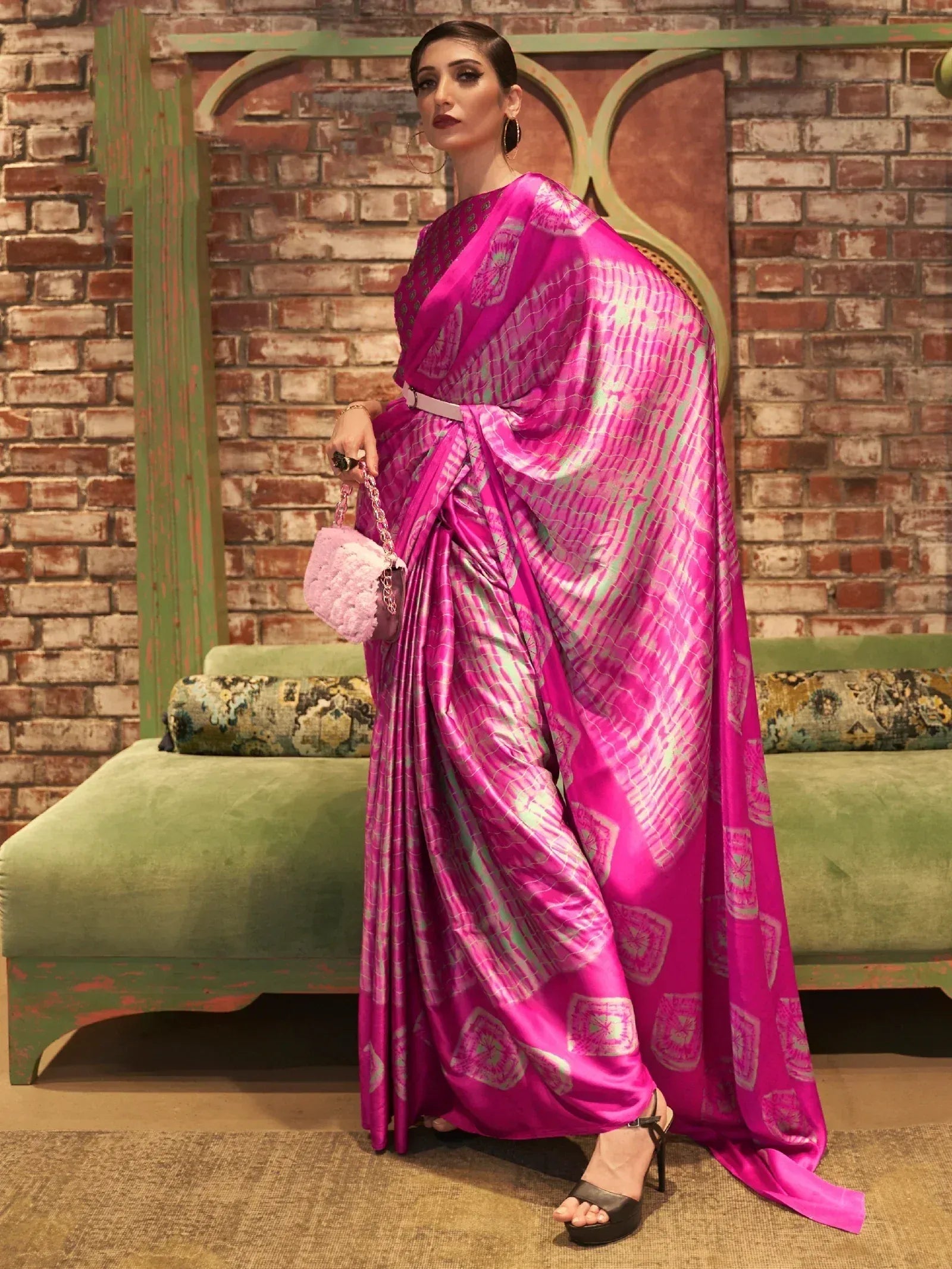 Vibrant pink printed saree with modern drape, styled with belt and pink handbag for ethnic wear