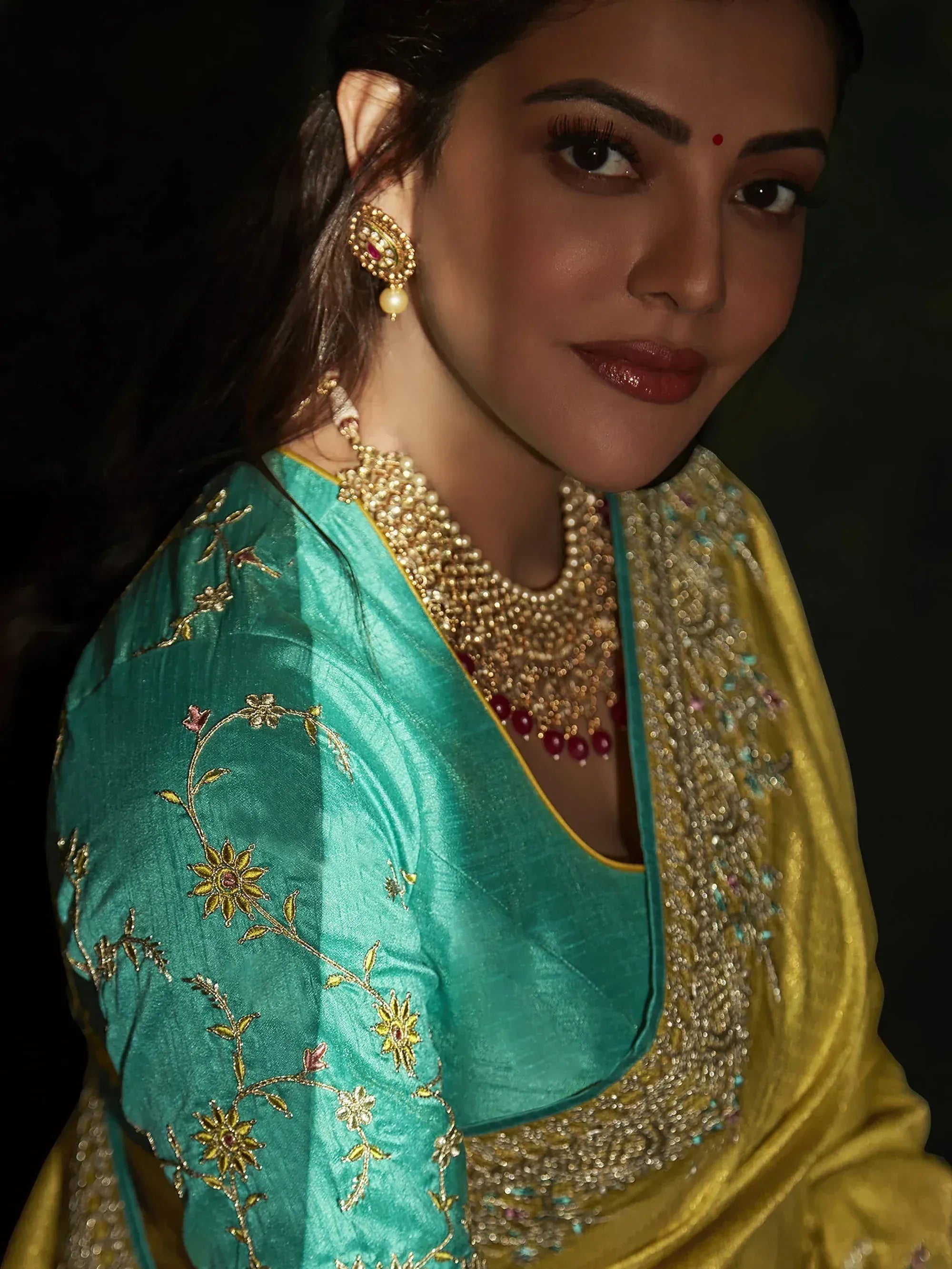 Teal and gold embroidered Indian ethnic wear with floral detailing and traditional jewelry