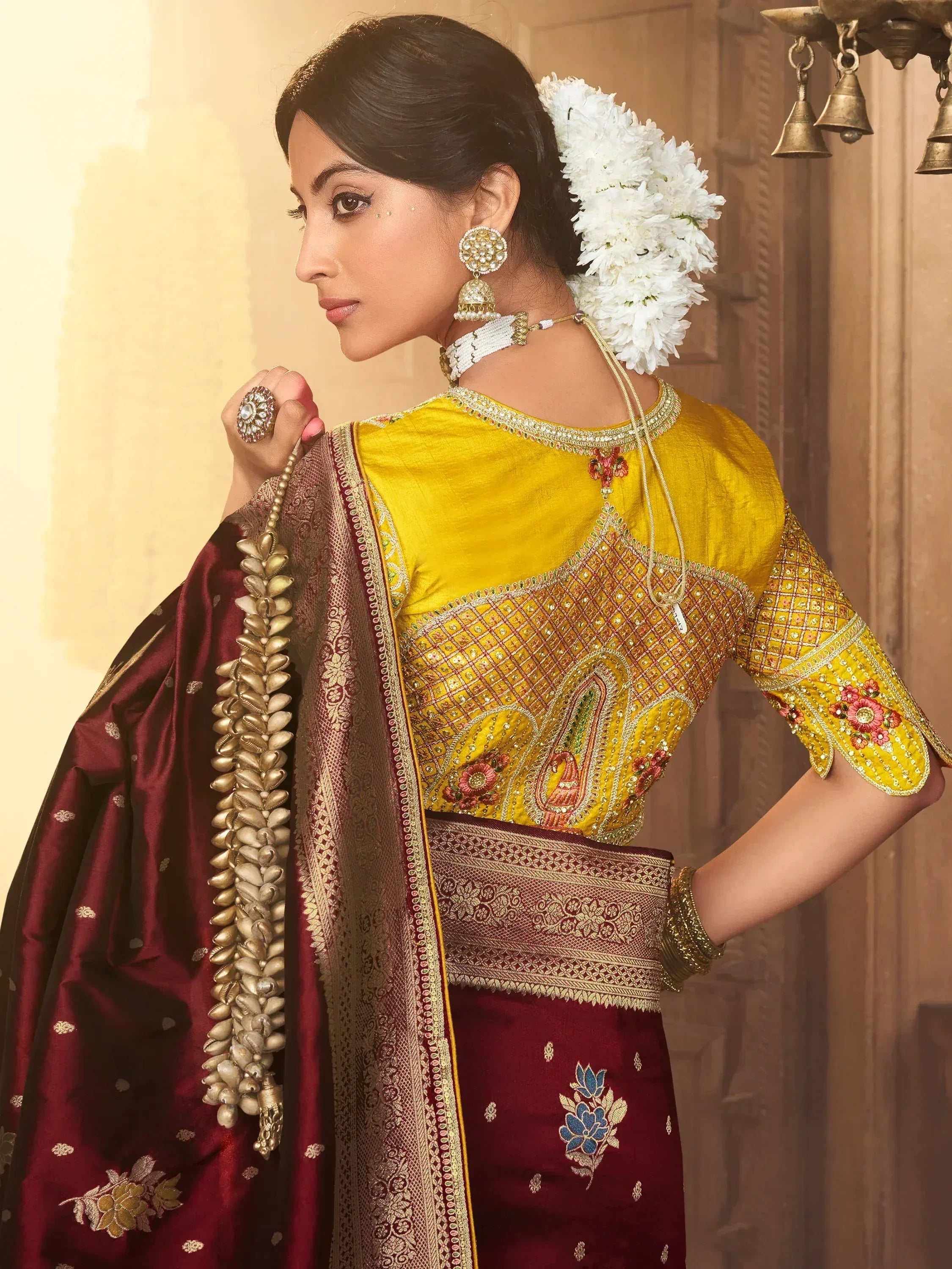Woman in yellow embroidered blouse and maroon saree with floral hair accessory, traditional Indian ethnic wear