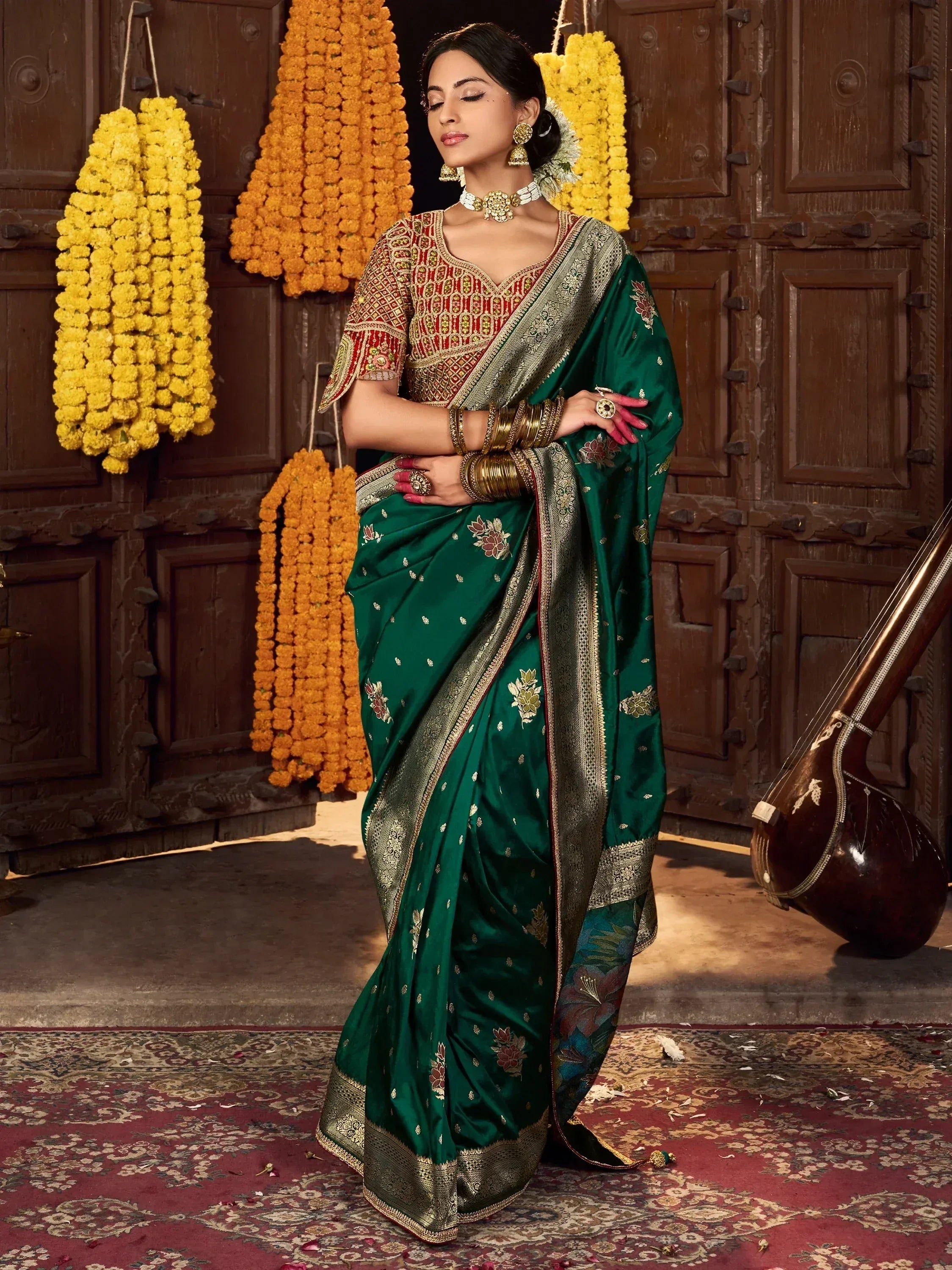 Elegant green silk saree with gold embroidery, paired with designer blouse, traditional jewelry, and floral garlands.
