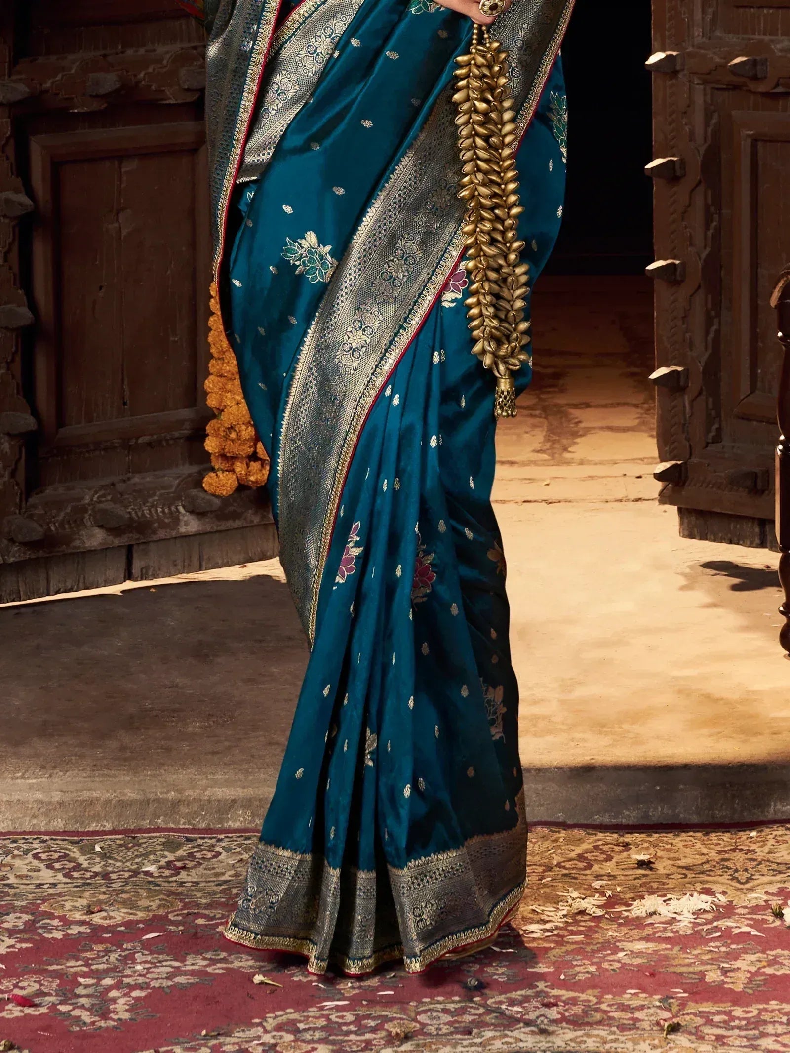 Teal silk saree with gold floral embroidery and heavy zari border, styled with traditional temple jewelry.