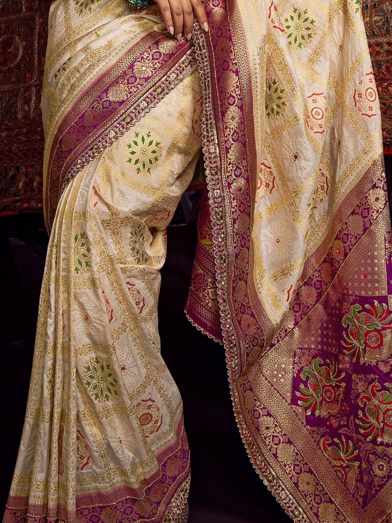 Cream and purple designer saree with gold zari, floral motifs, and intricate border for Indian ethnic wear