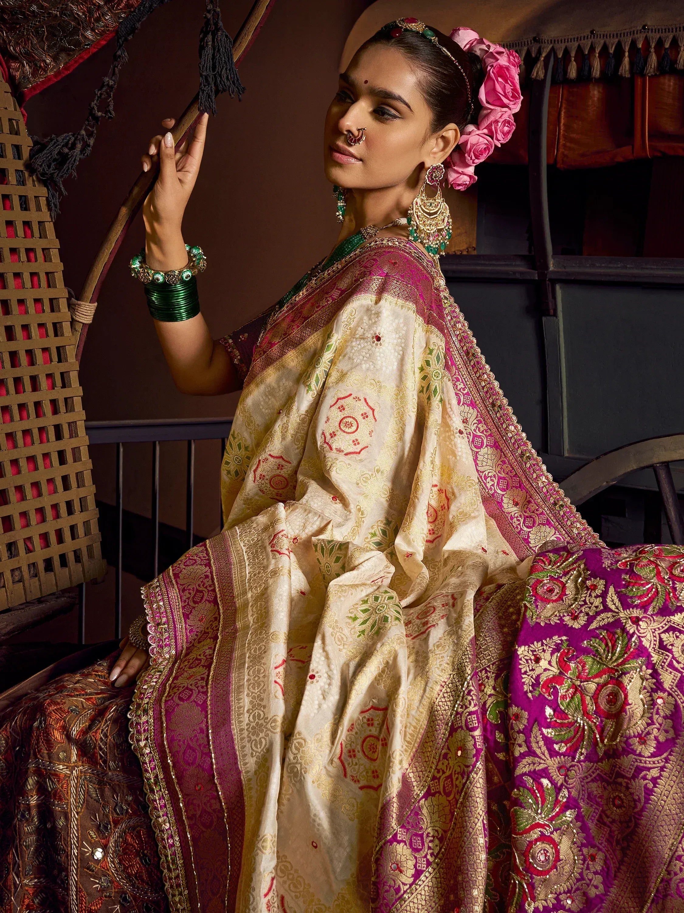 Elegant Indian woman in designer saree with gold embroidery, pink floral hair, and traditional jewelry.