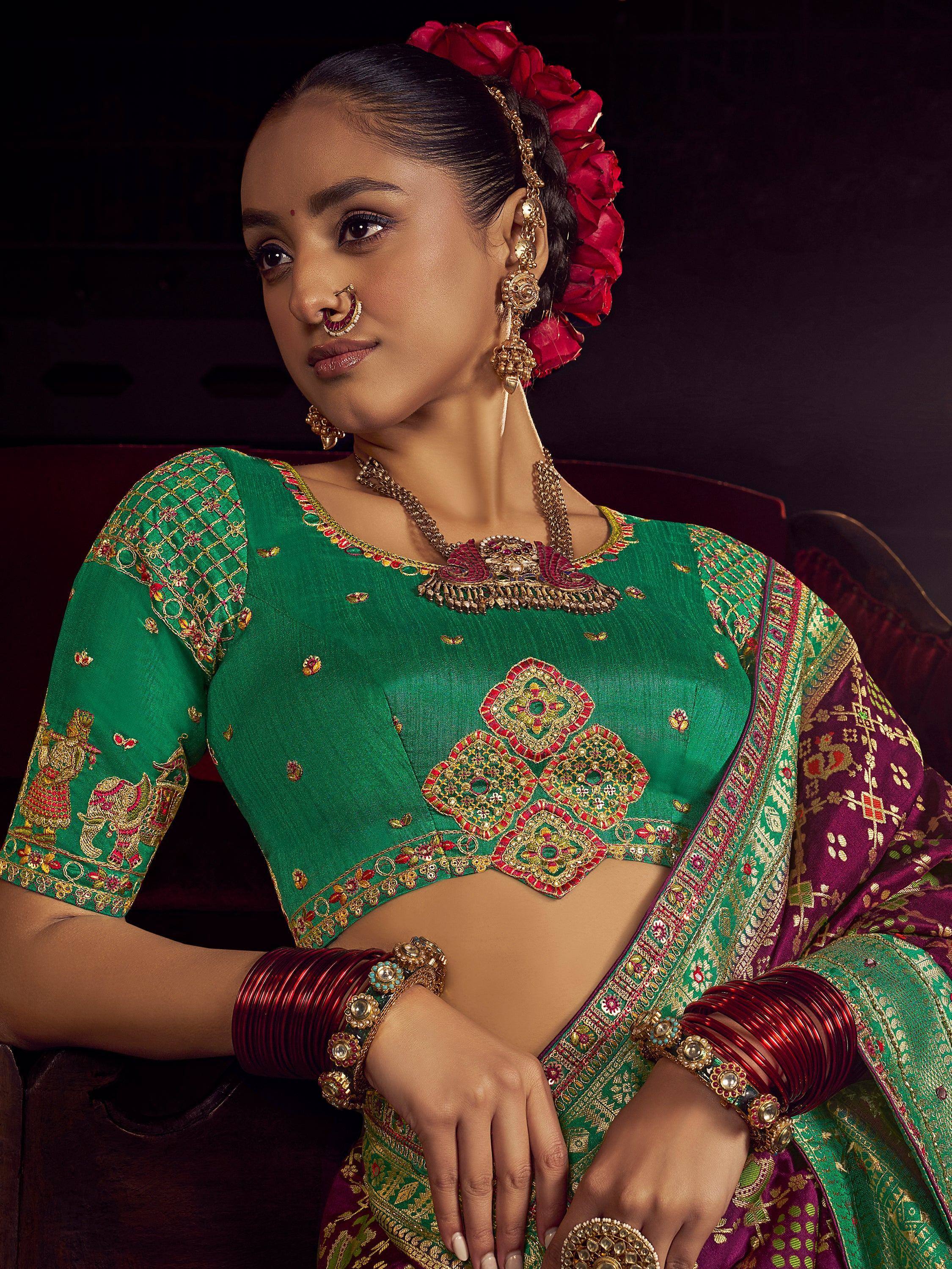 Elegant green and maroon embroidered saree with gold jewelry and floral hair accessory for Indian ethnic wear