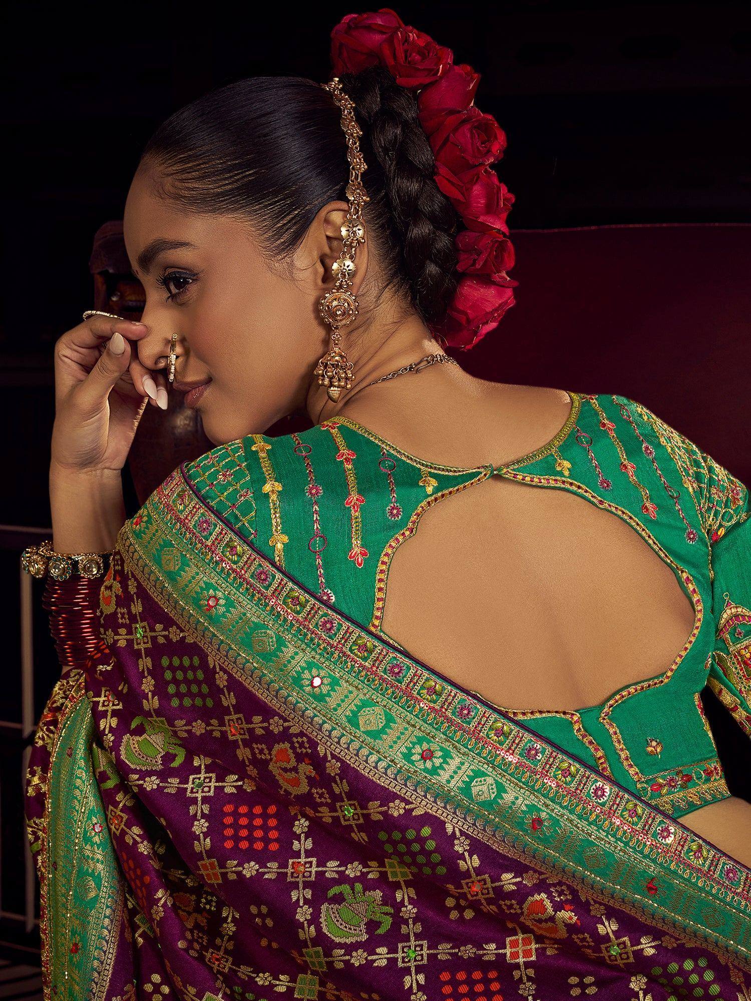 Green and purple embroidered saree with back cutout, floral hair accessory, and gold jewelry