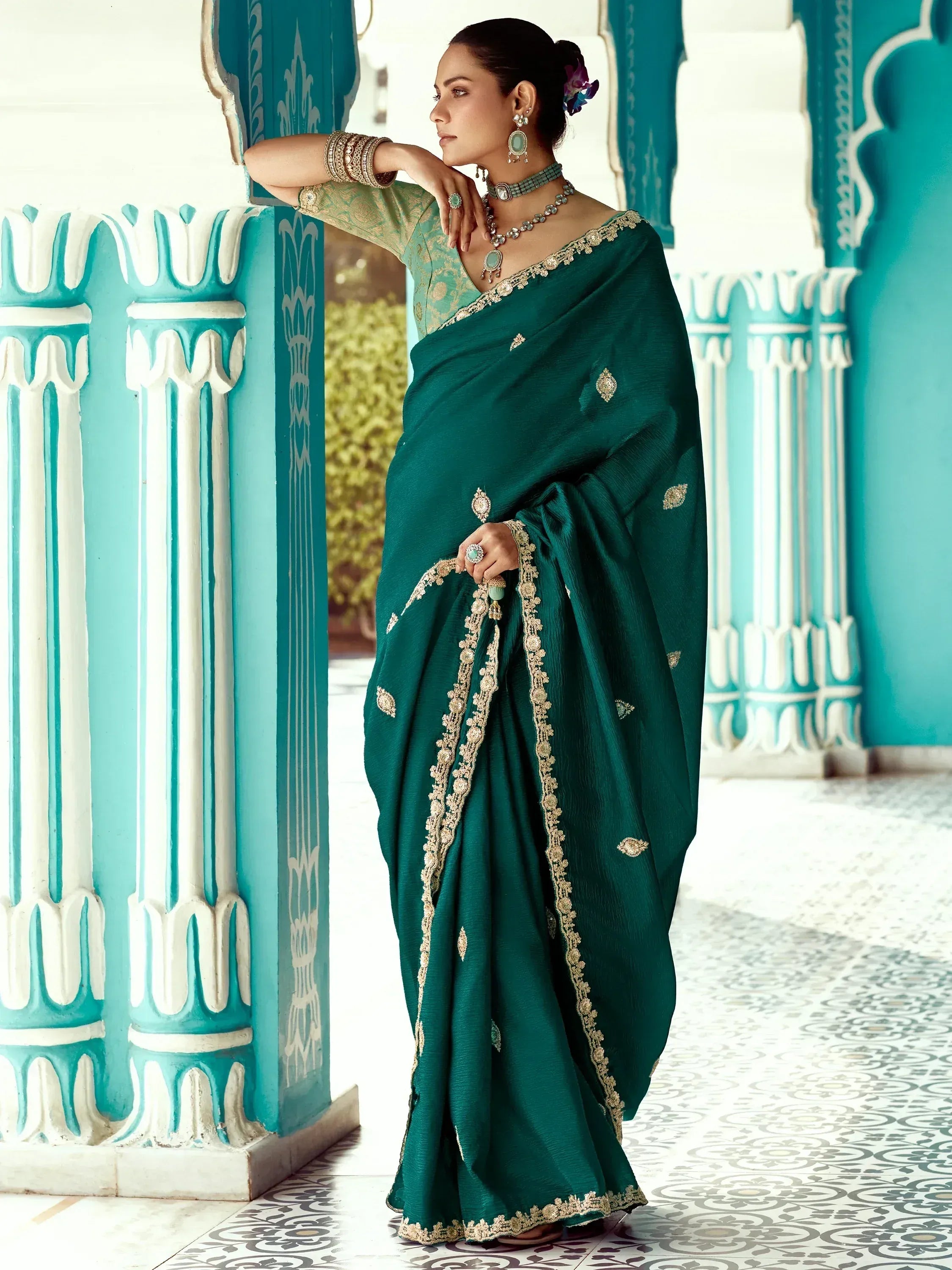 Emerald green designer saree with gold embroidery, paired with matching blouse and traditional jewelry, perfect for Indian ethnic occasions.