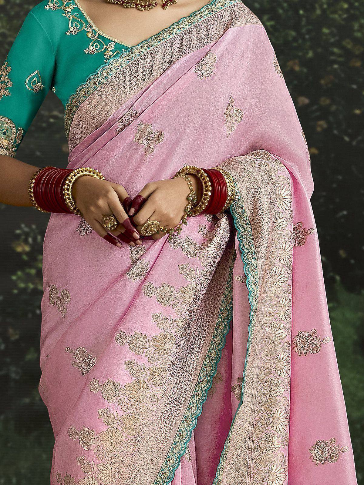 Pink floral embroidered saree with teal blouse, gold detailing, and traditional Indian jewelry