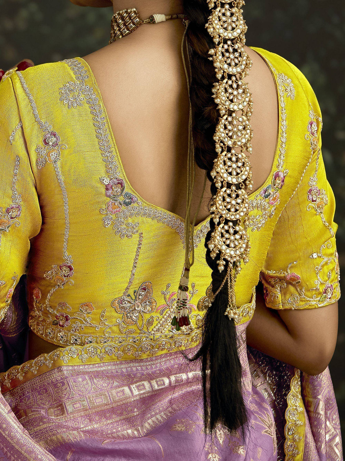 Yellow embroidered blouse with deep back, floral motifs, and pearl hair accessory for Indian ethnic wear