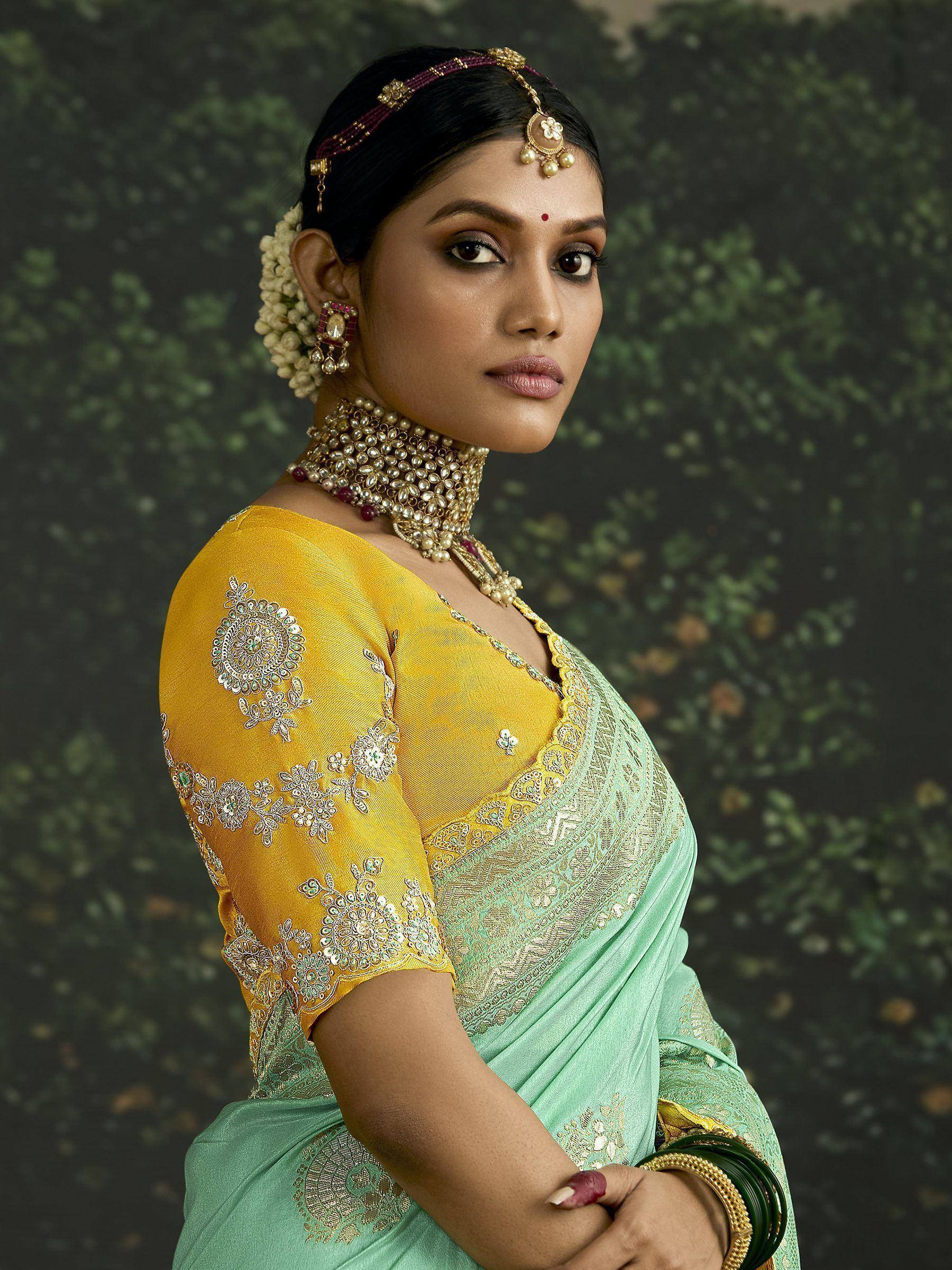 Woman in mint green saree with yellow embroidered blouse, traditional Indian jewelry, floral hair accessory