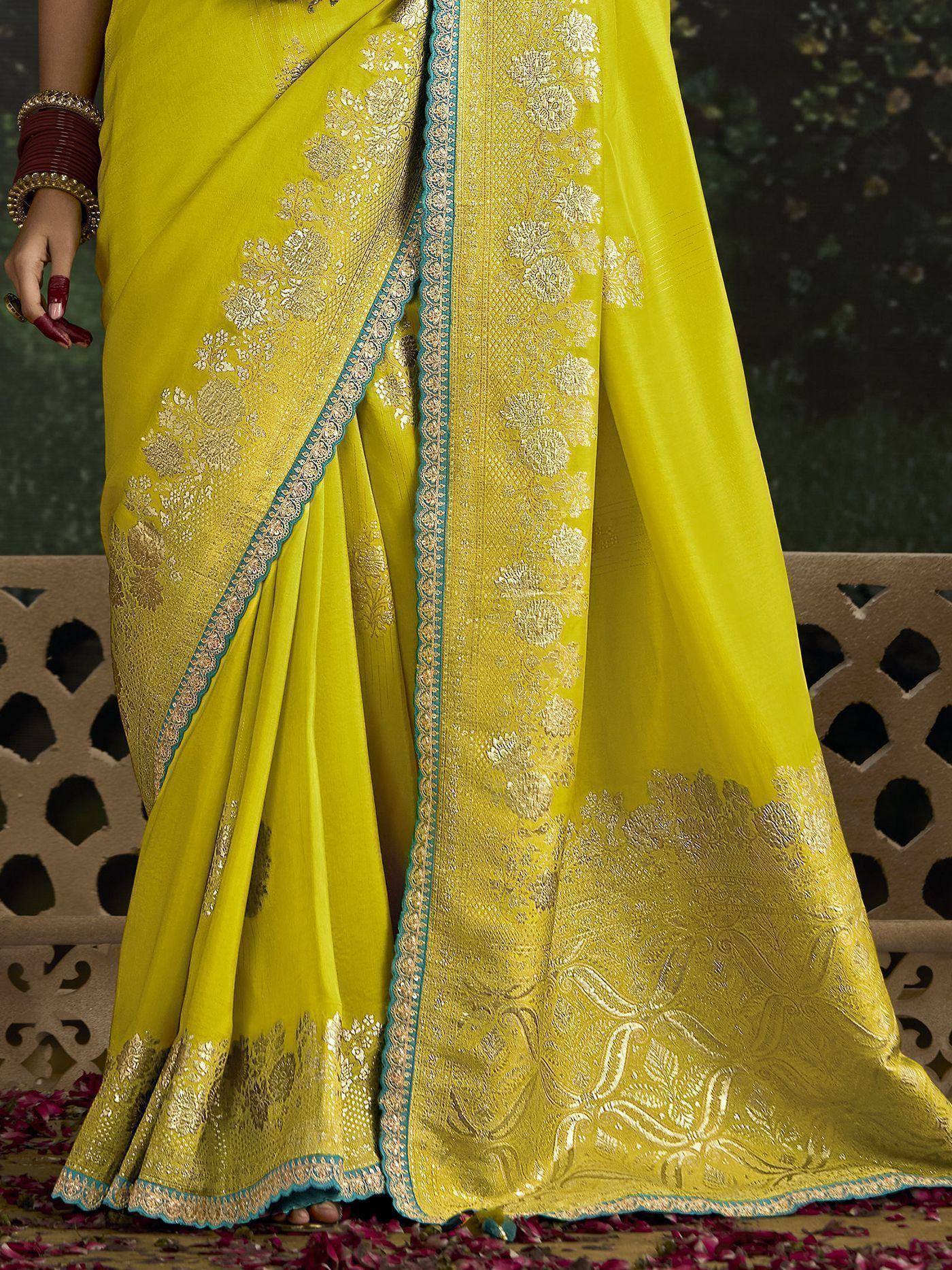 Vibrant yellow saree with gold floral embroidery and blue border, styled with bangles for ethnic wear