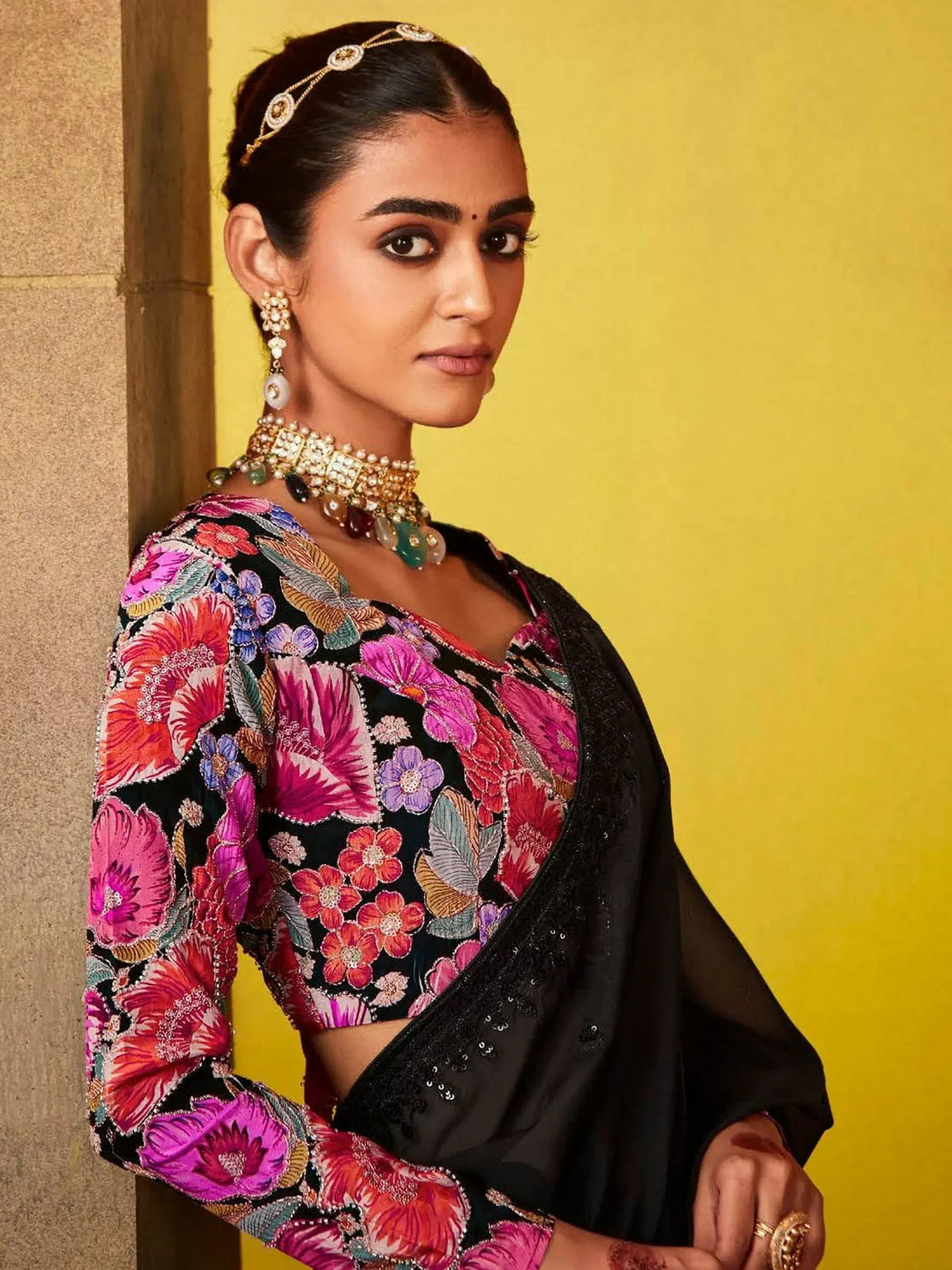 Woman in vibrant floral embroidered black saree with traditional jewelry, perfect for Indian ethnic wear occasions